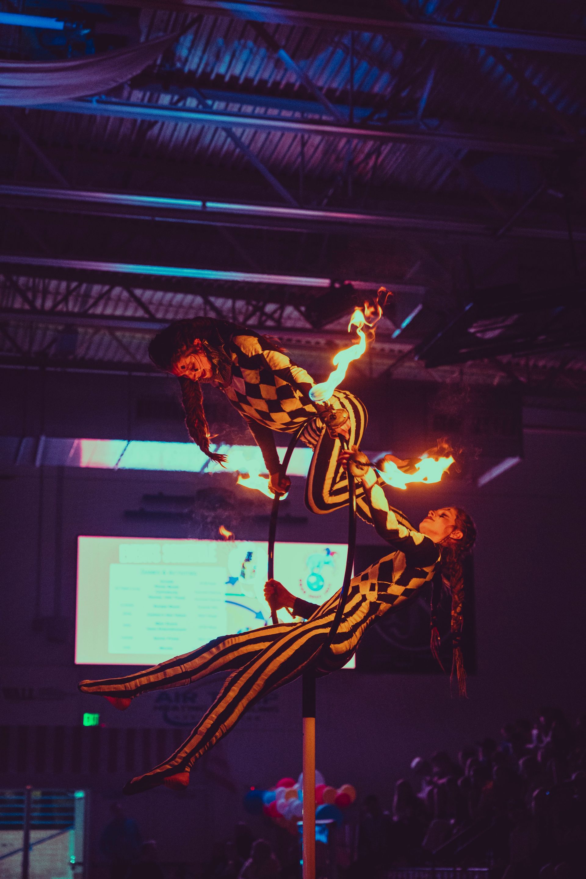 A couple of people are standing on a pole with fire coming out of them.