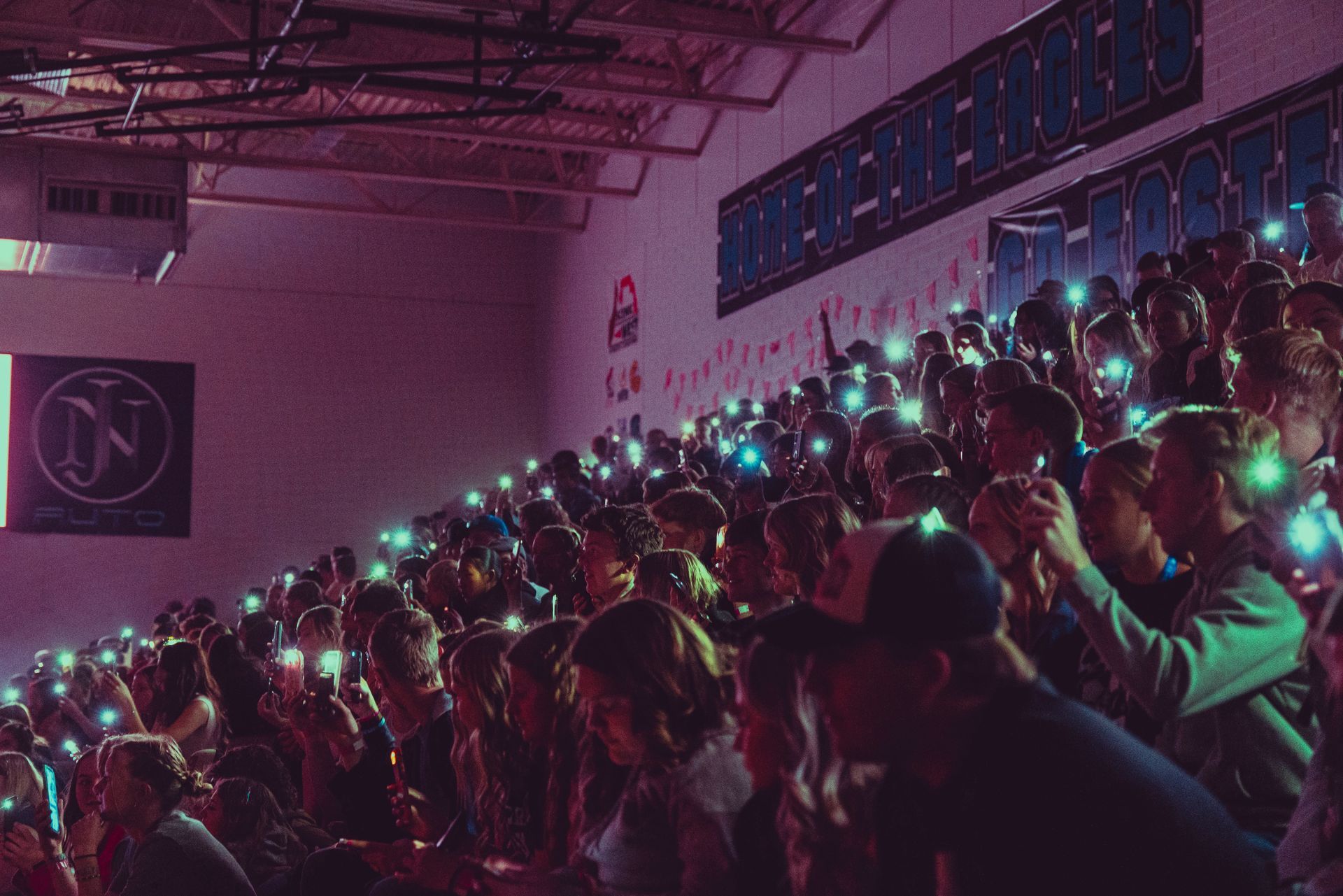 A crowd of people are sitting in a stadium with their phones in their hands.