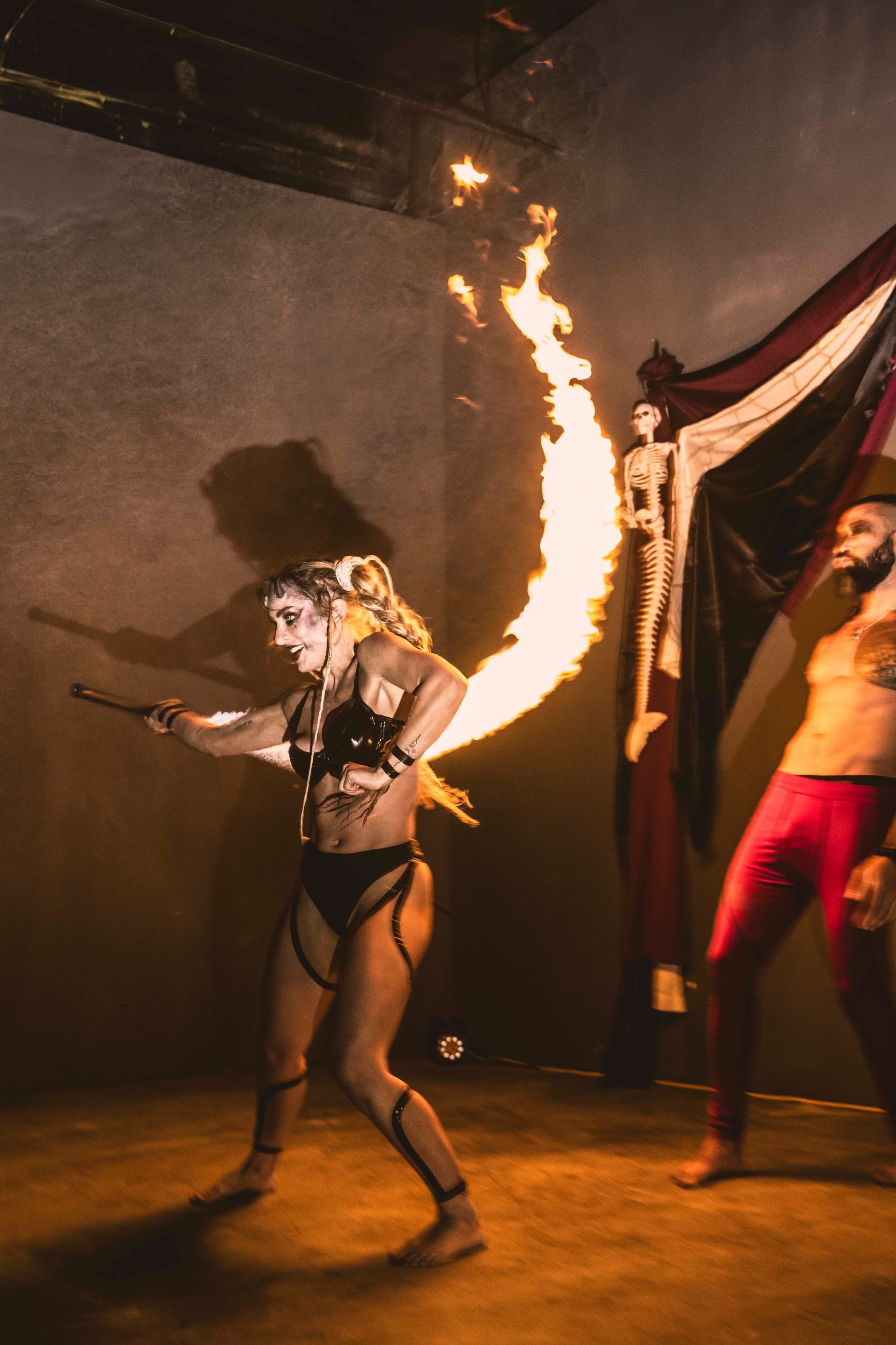 A woman is holding a stick with fire coming out of it.