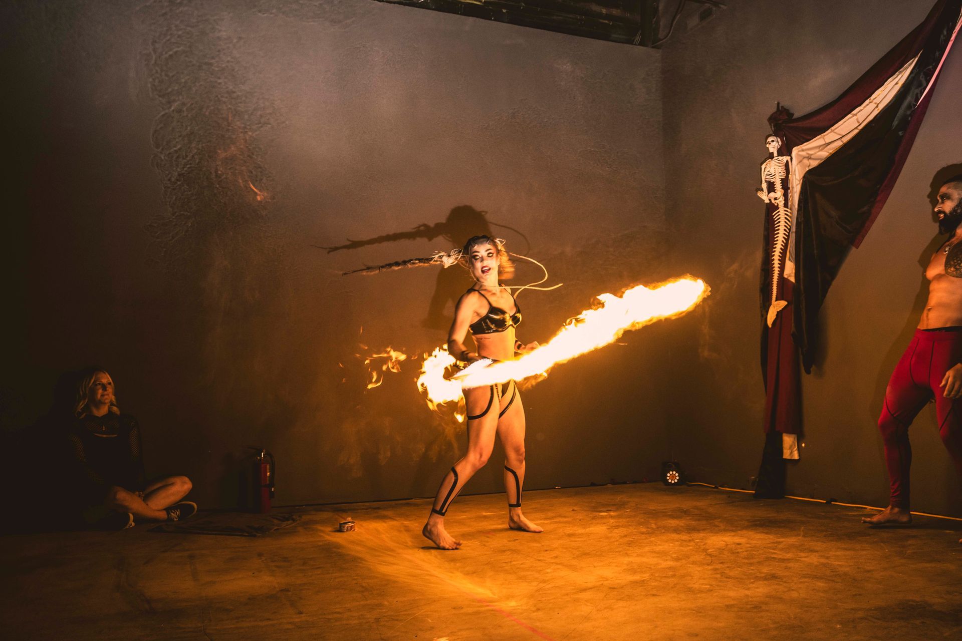 A woman dressed as a succubus performing with a fire sword.