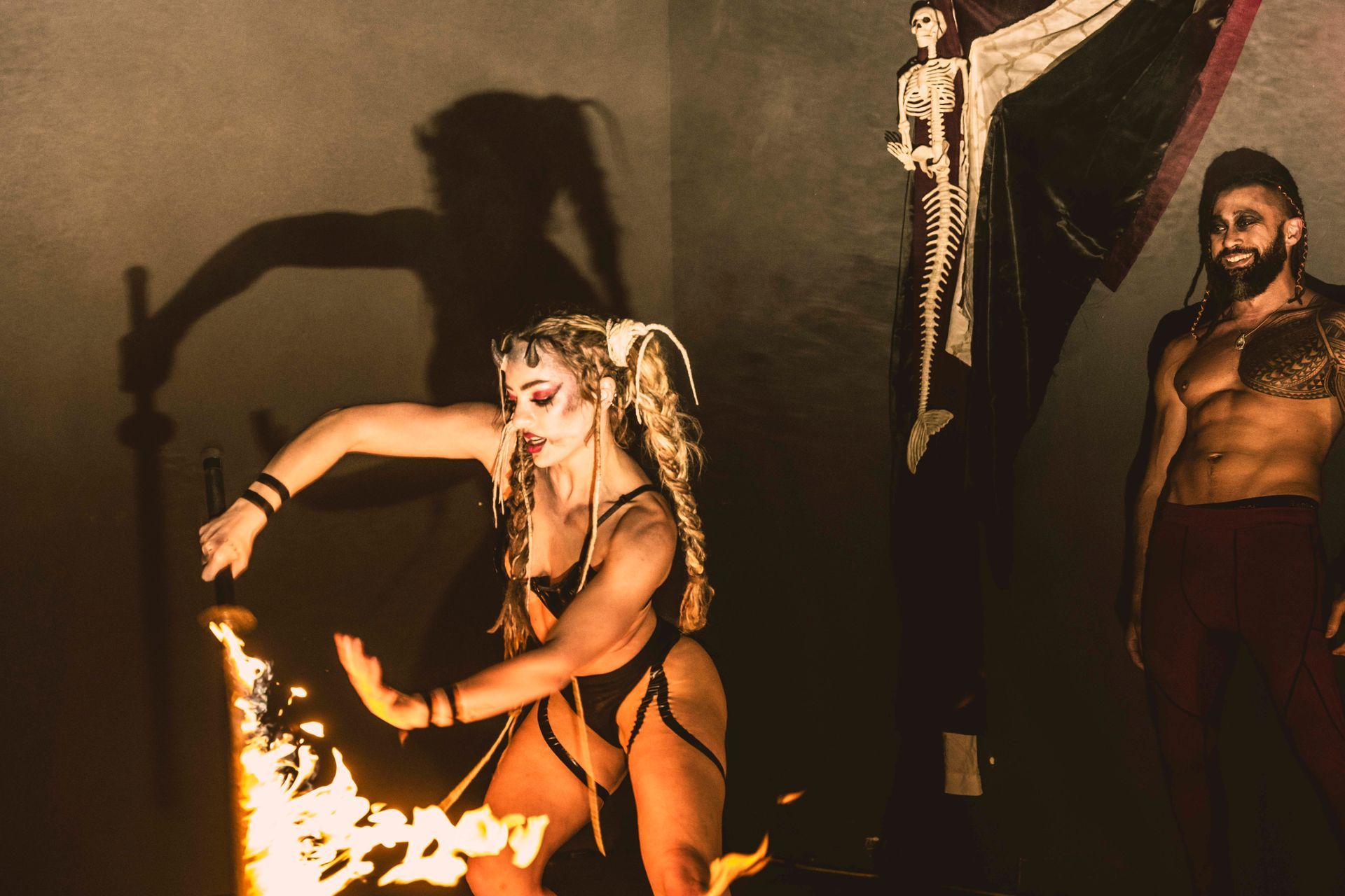 A man and a woman are dancing in front of a skeleton.