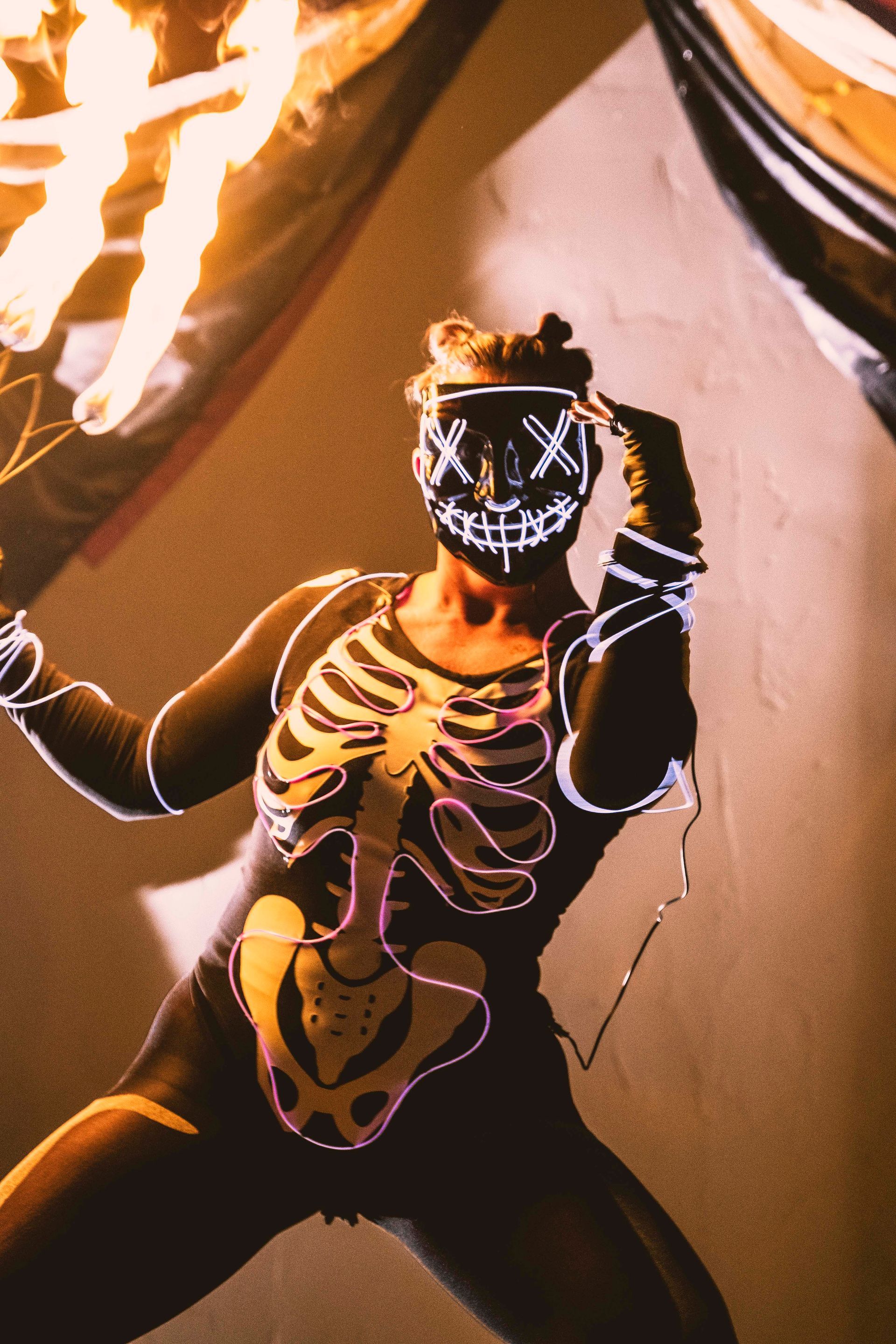 A person wearing a skeleton costume and a neon mask