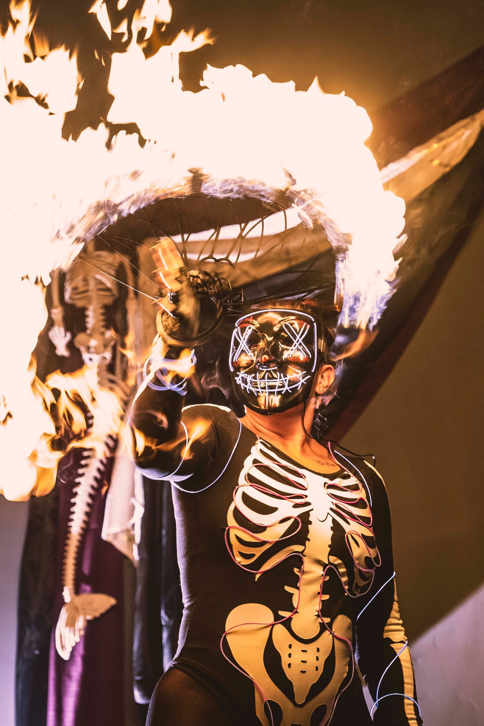 A person dressed as a skeleton is holding a torch with flames coming out of it.