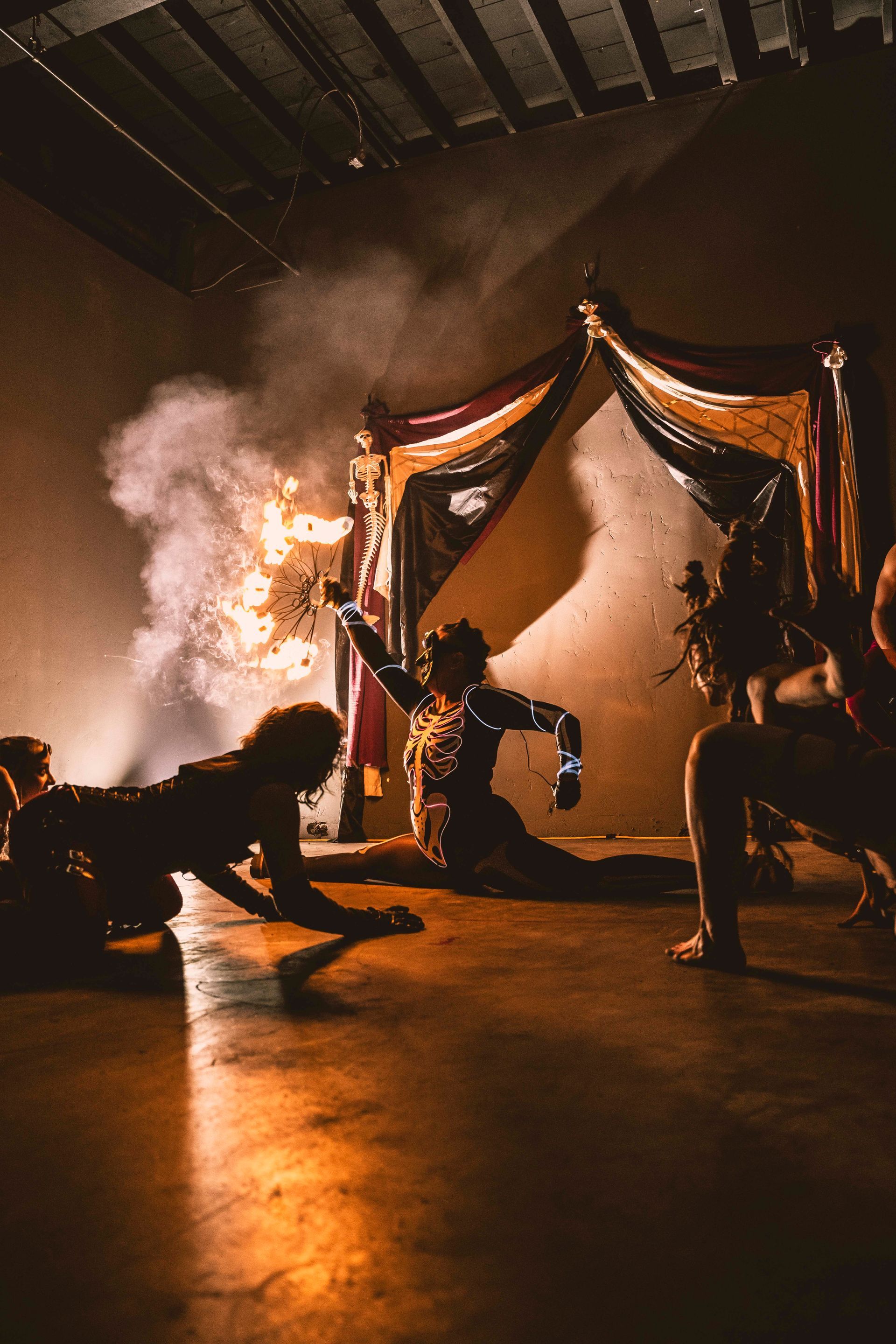 A group of people are dancing in a dark room with smoke coming out of the ceiling.