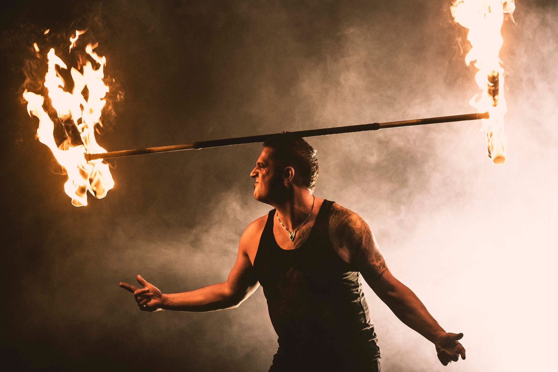 A man is juggling two sticks of fire on his head.
