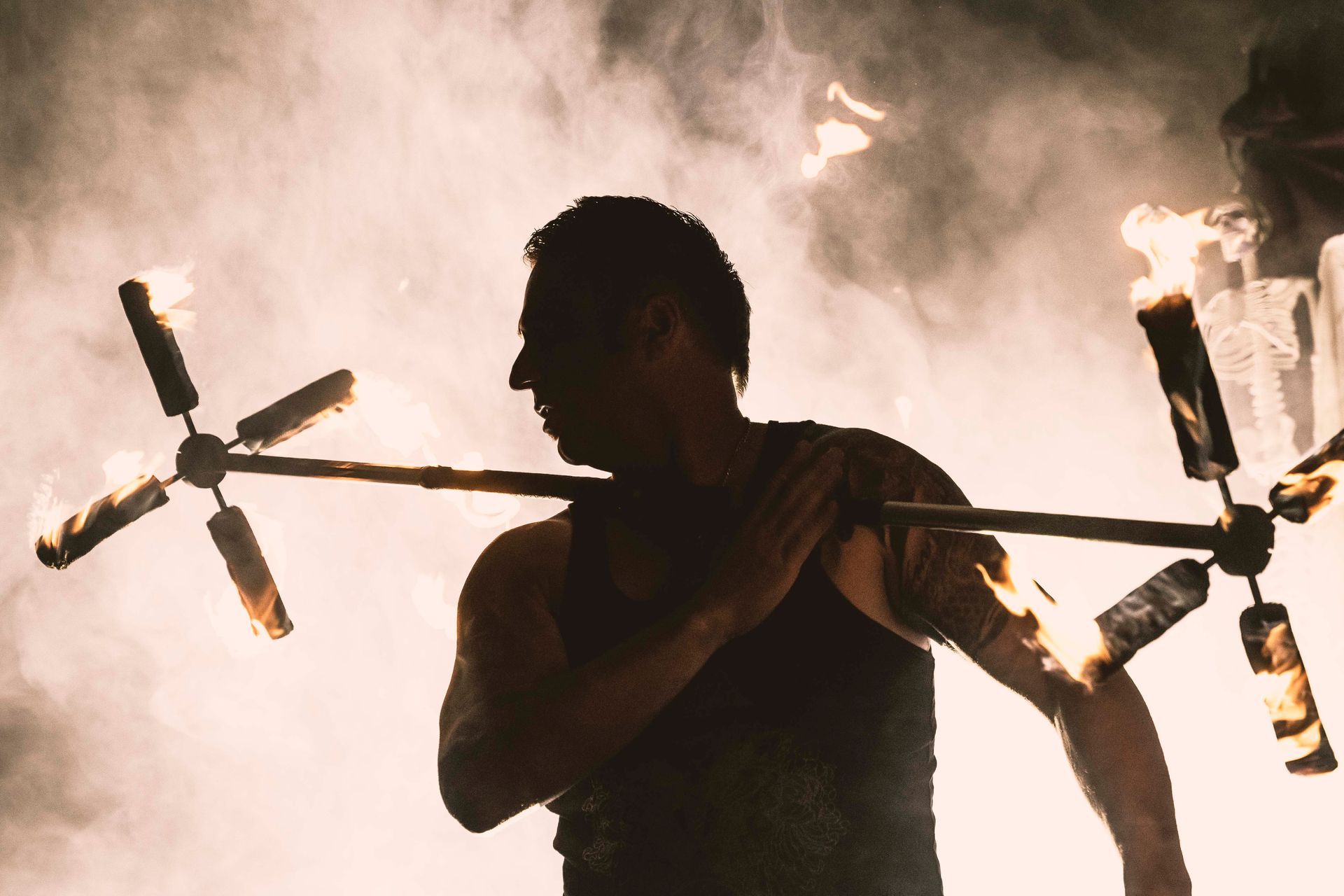 A man is holding a stick with fire coming out of it.