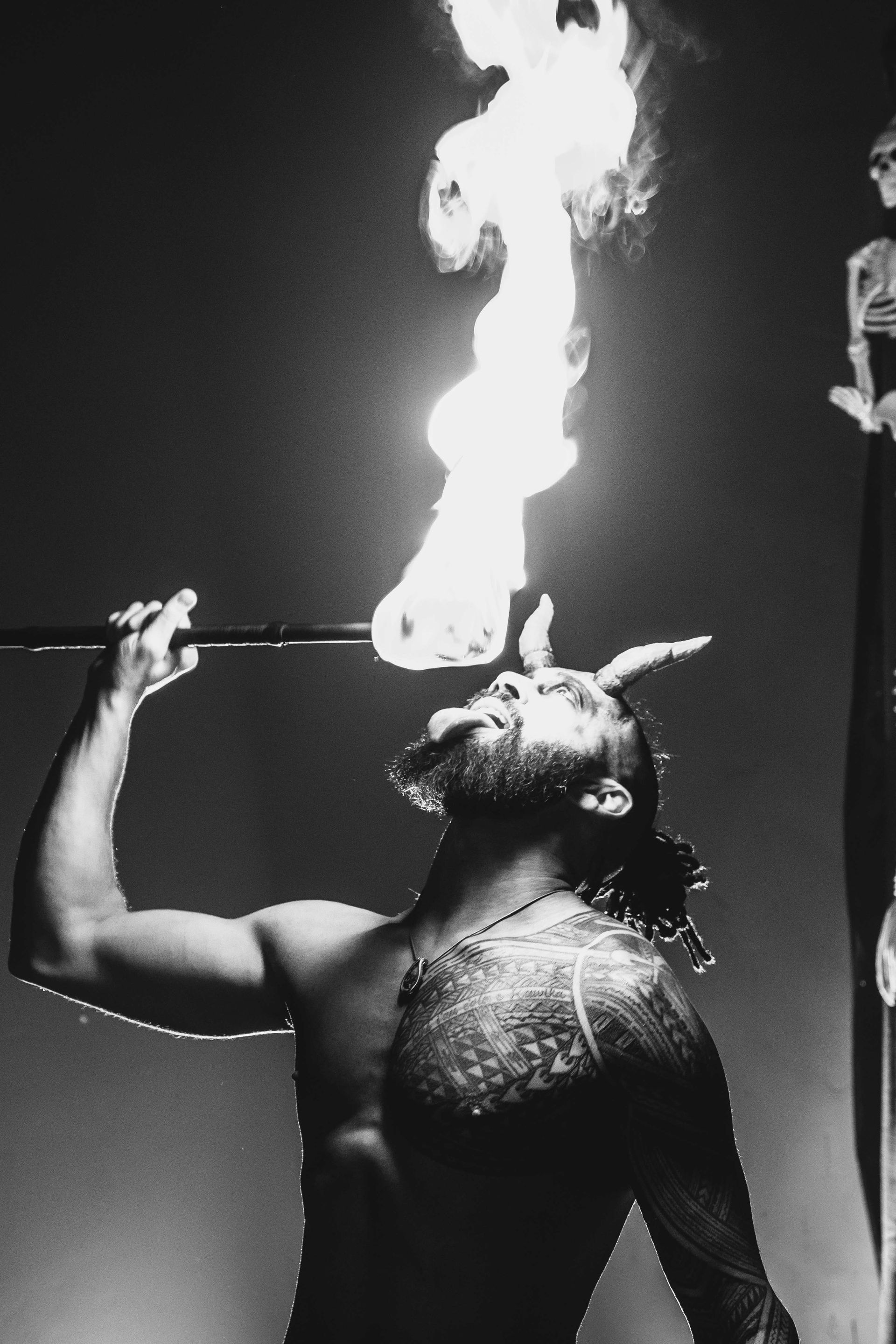 A man with horns is holding a stick with flames coming out of it