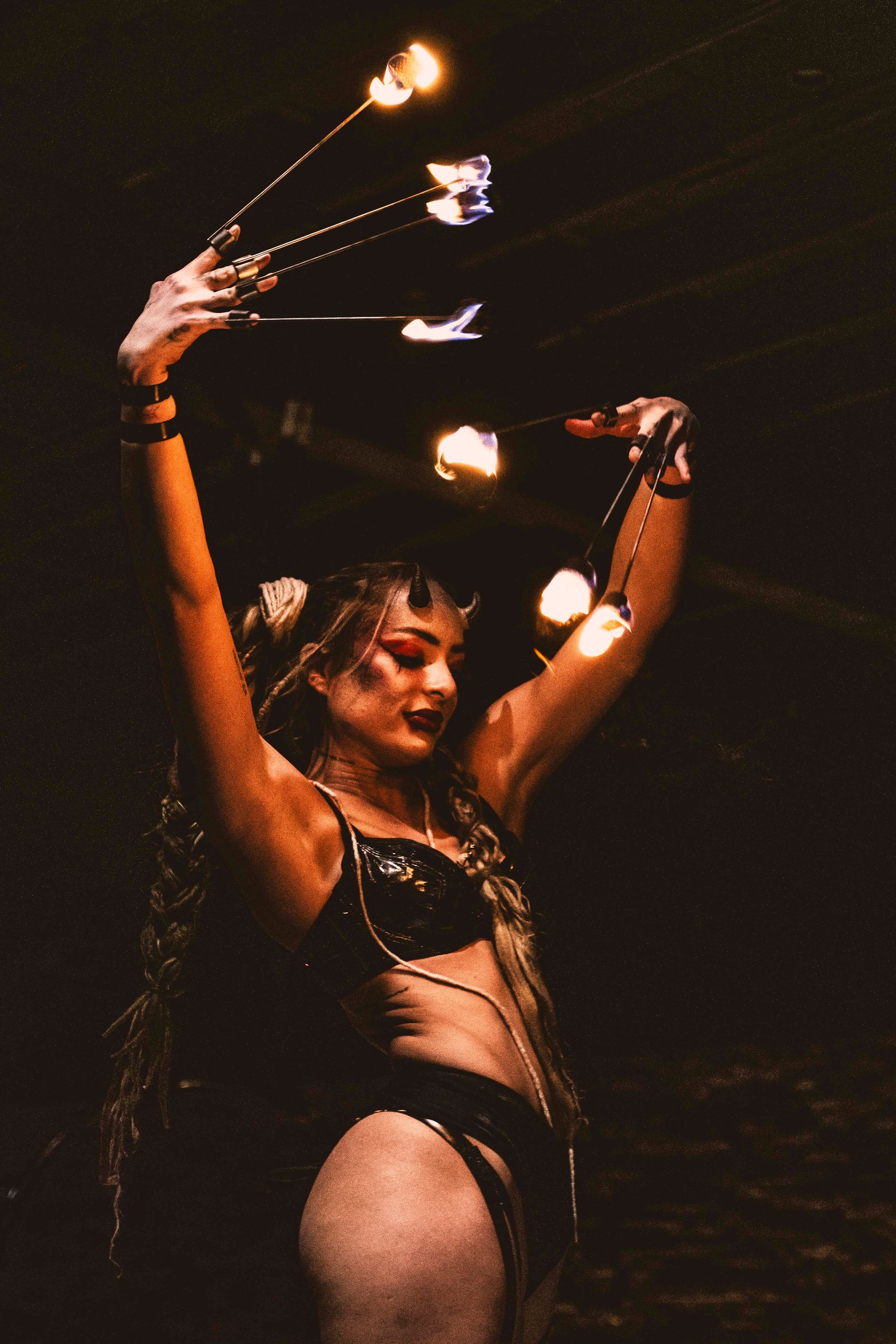 A woman performing as a succubus with fire fingers.