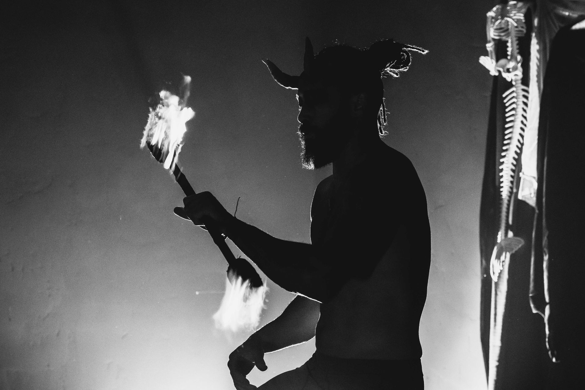 A black and white photo of a man with horns holding a torch
