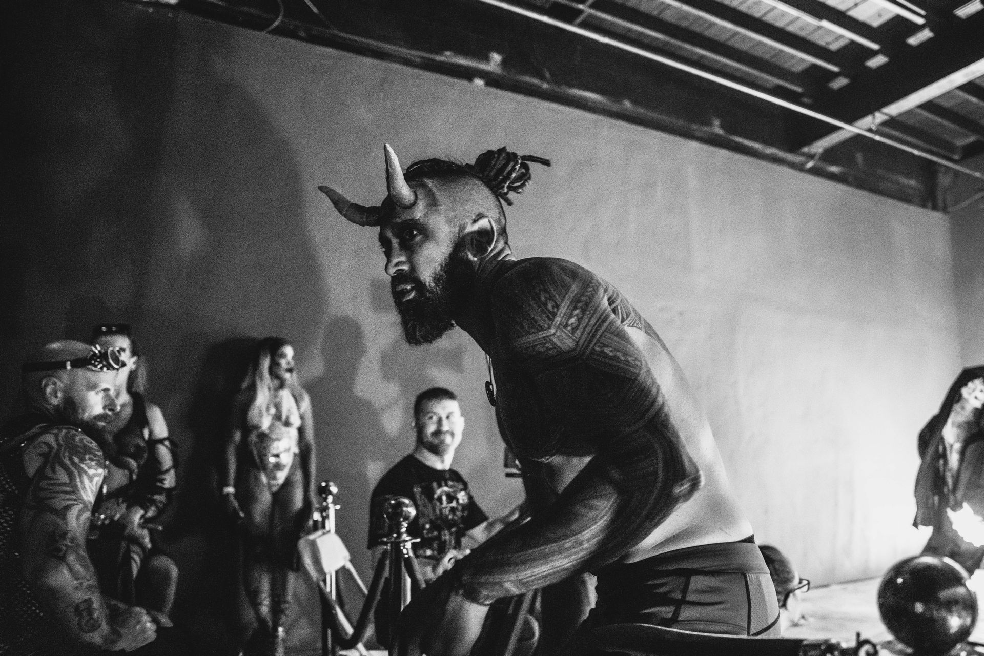 A man with horns is kneeling down in front of a group of people.
