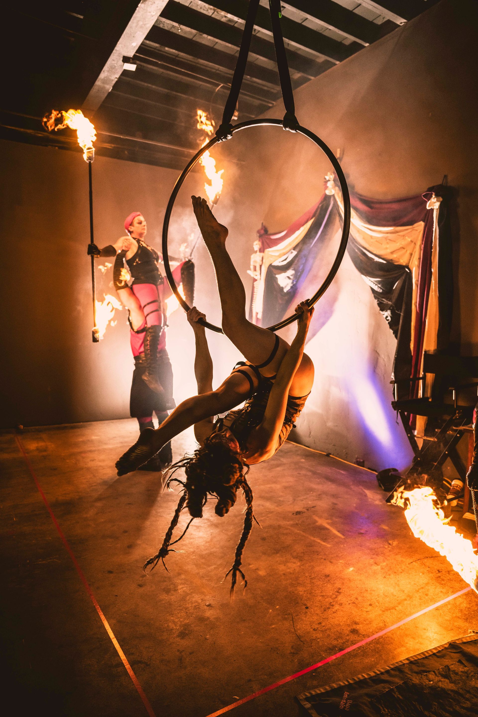 A woman is hanging upside down in an aerial hoop.