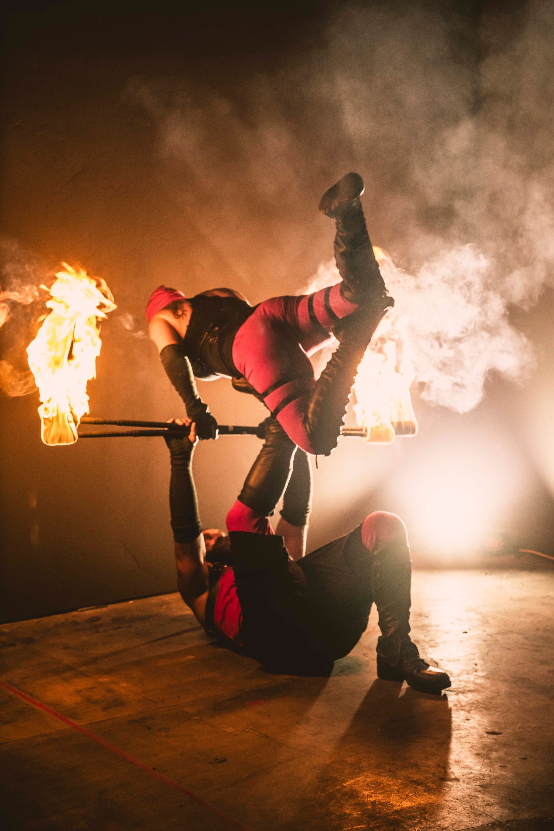 A man and a woman are doing a handstand in front of a fire.