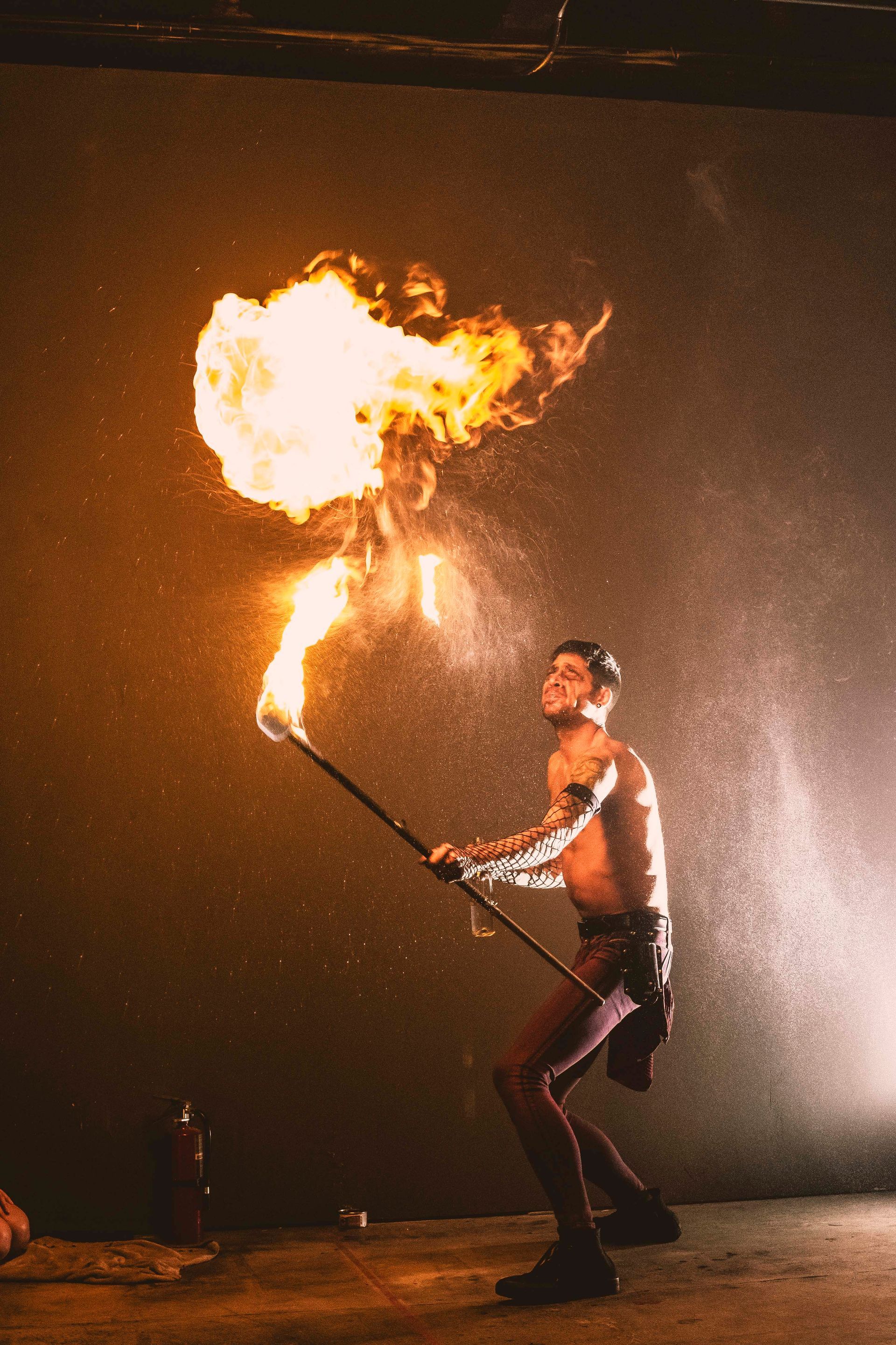 A man is holding a stick with flames coming out of it.