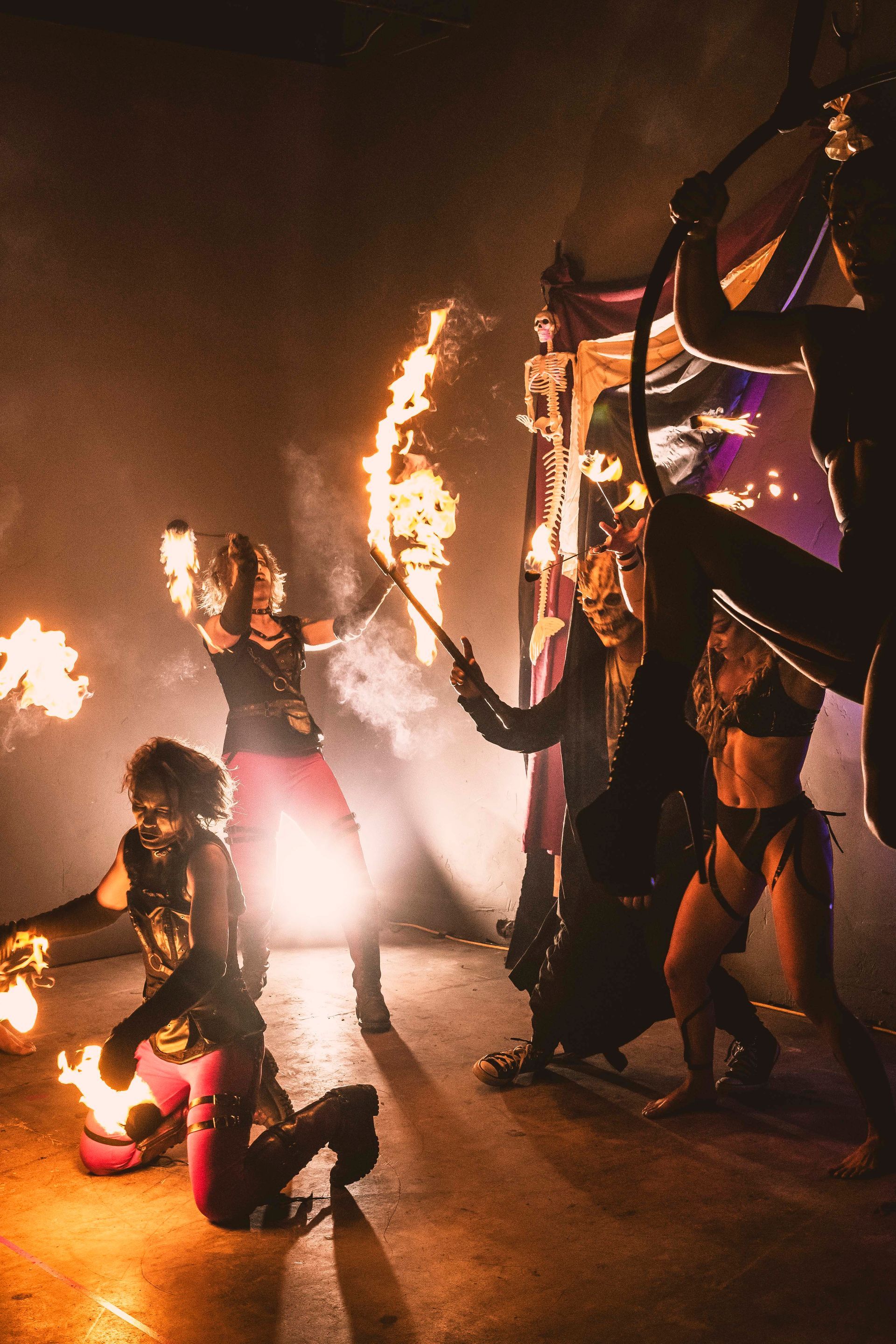 A group of people are dancing with fire in a dark room.