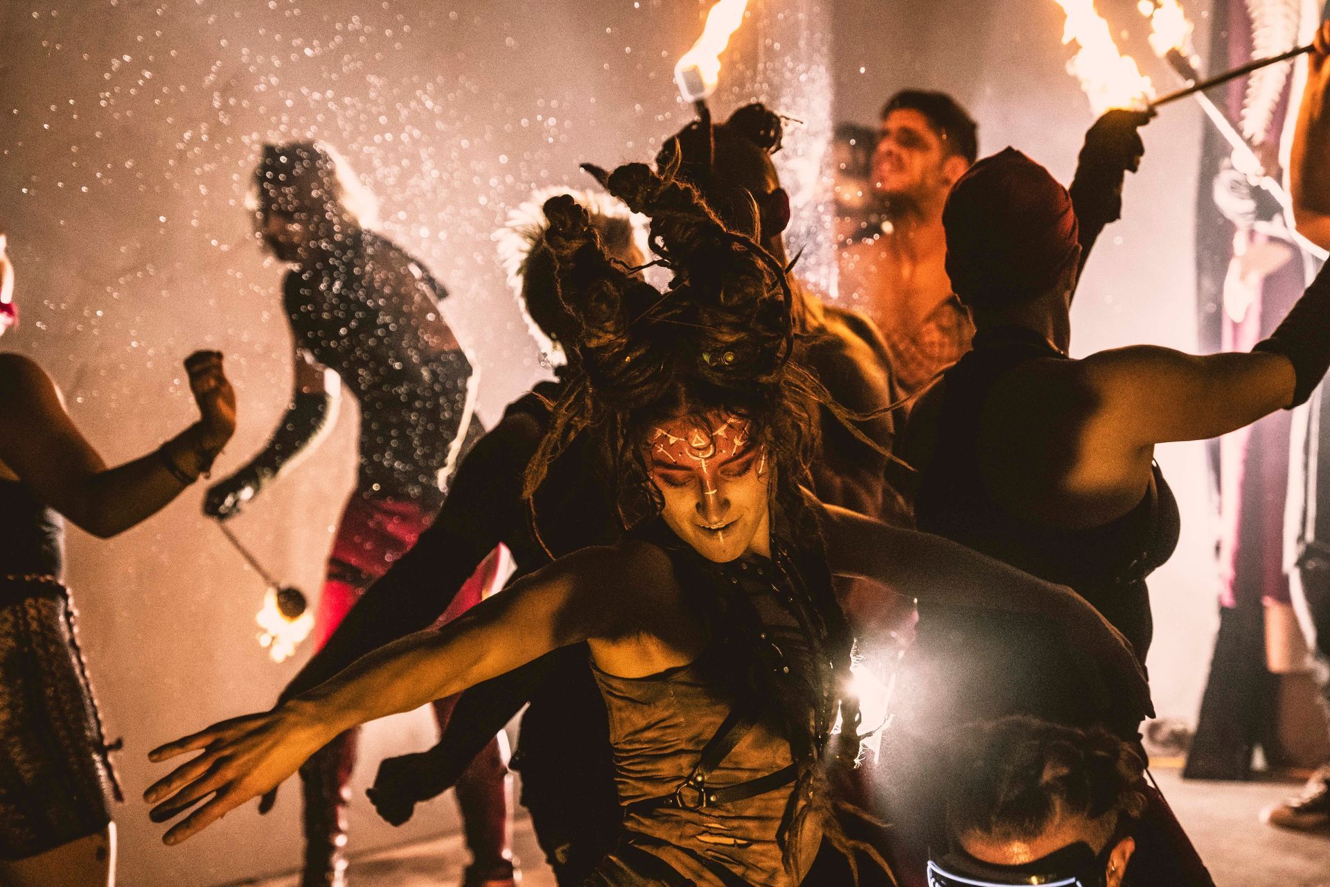 A group of people are dancing with fire in a dark room.