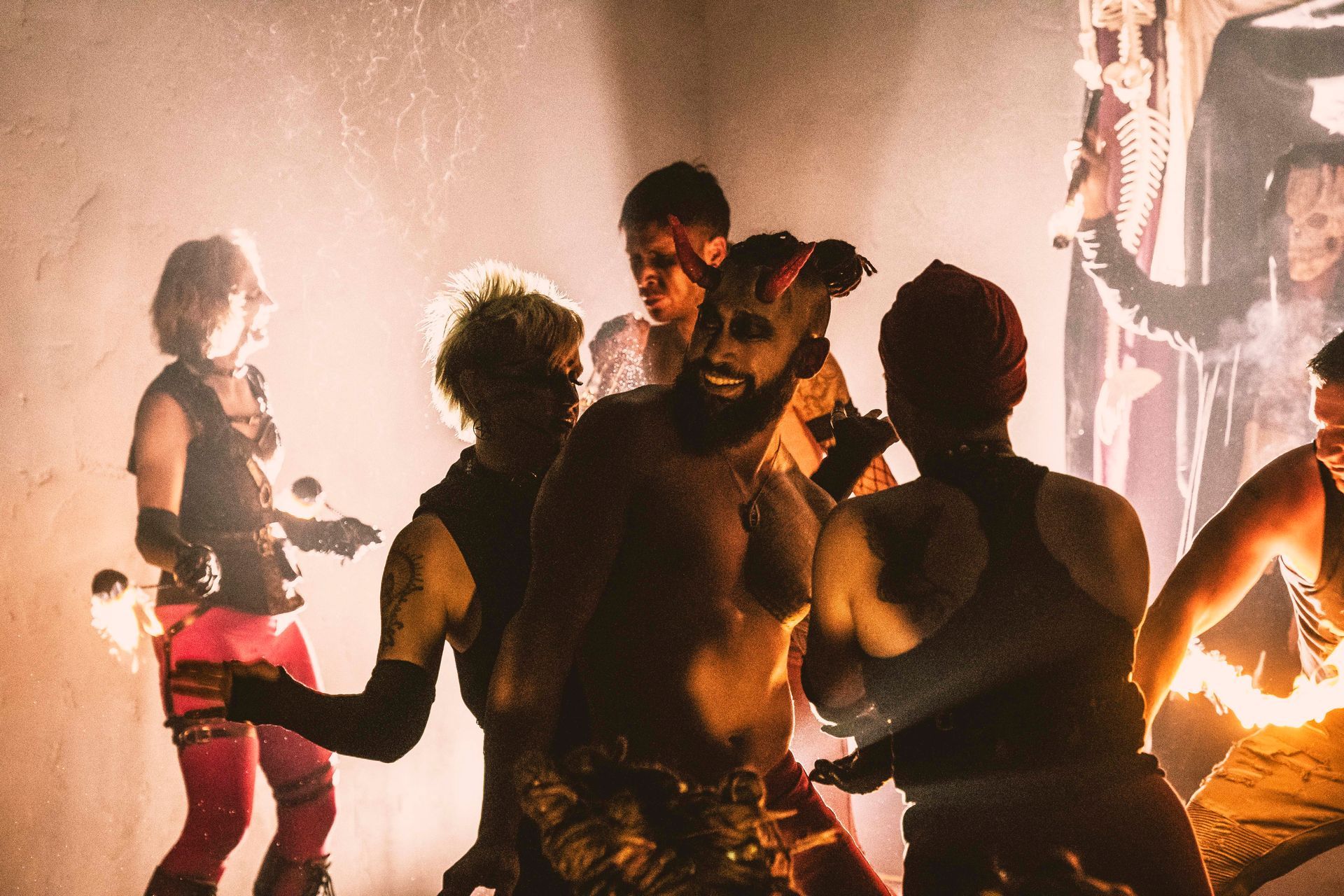 A group of people are dancing with fire in a dark room.