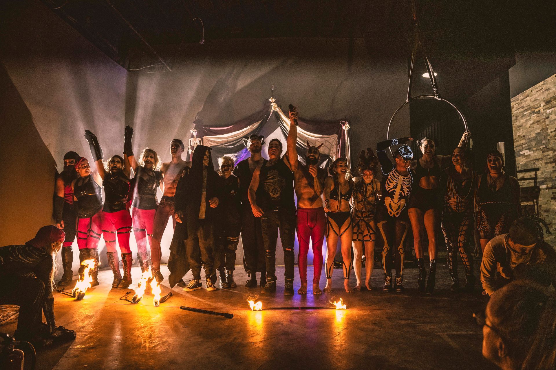 A group of people are standing around a fire in a dark room.