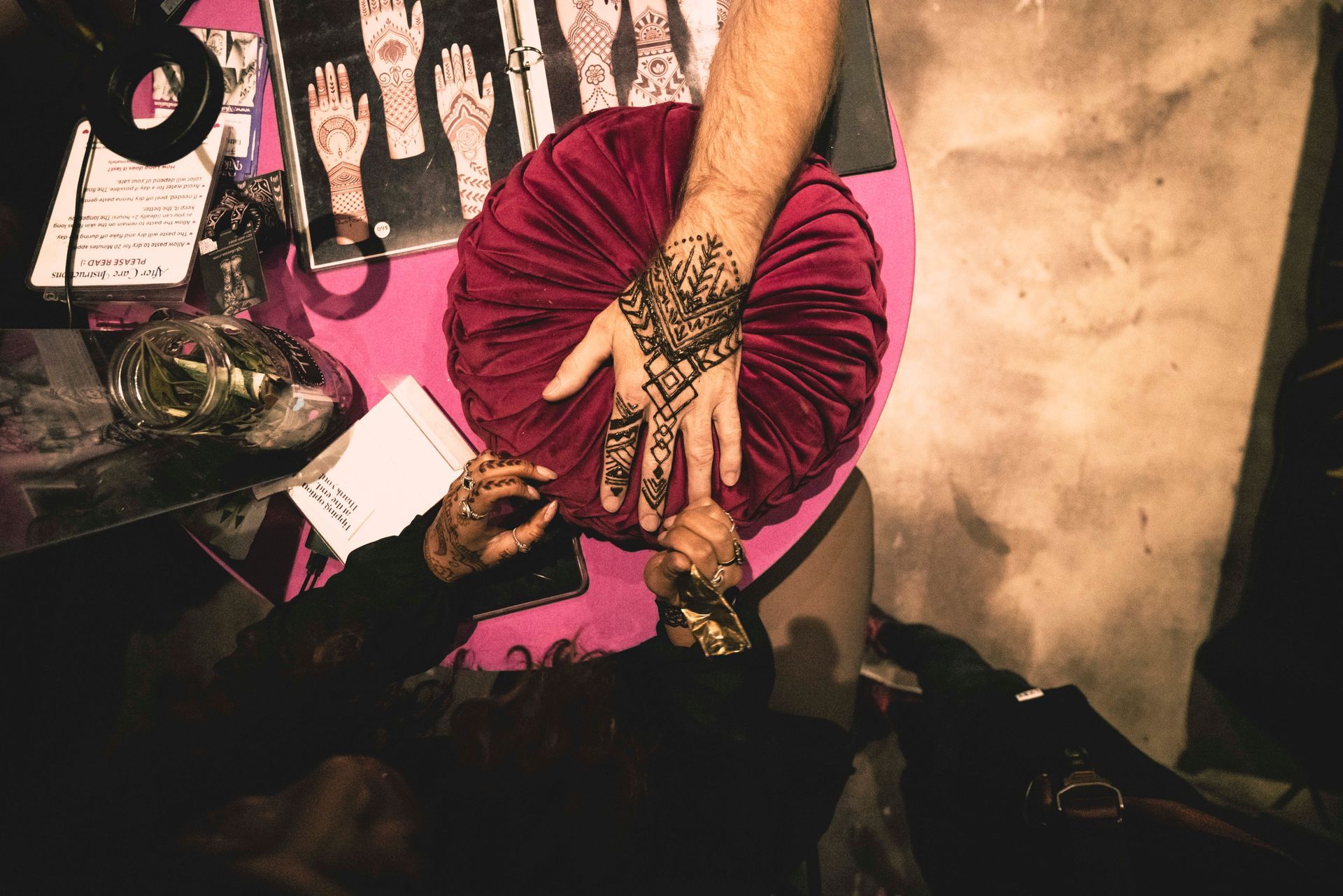 A person with a tattoo on their hand is holding a red pillow.