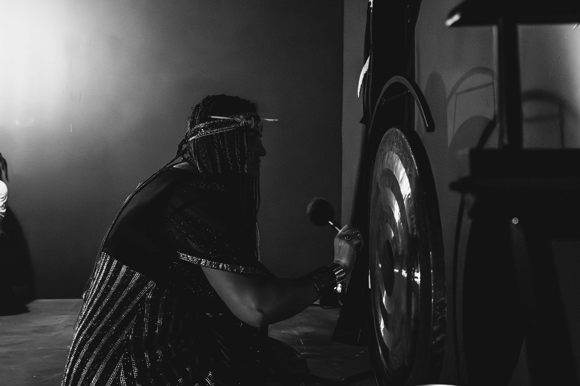 A black and white photo of a woman changing a tire on a car.
