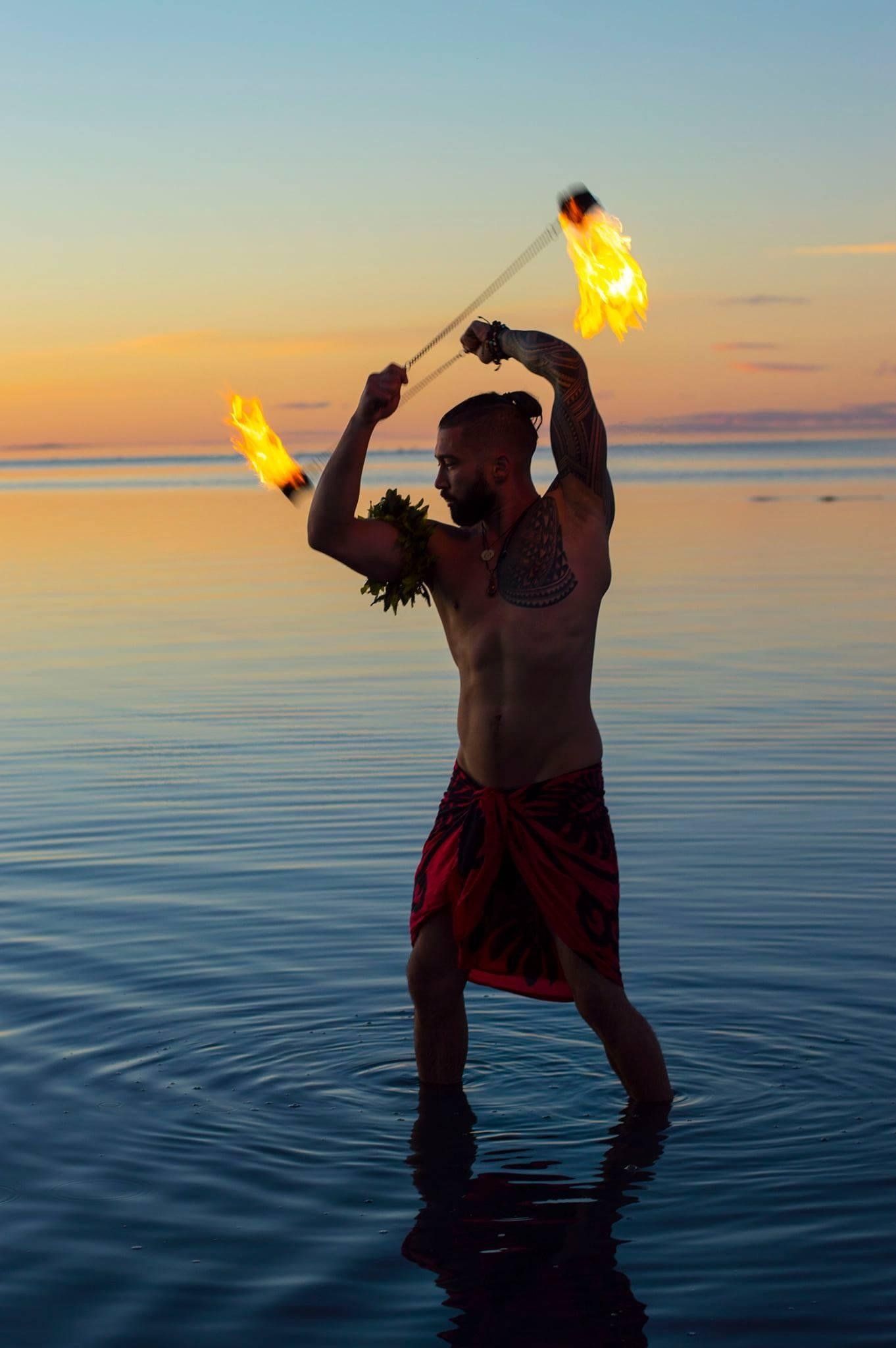 A man is standing in the water holding a fire stick.
