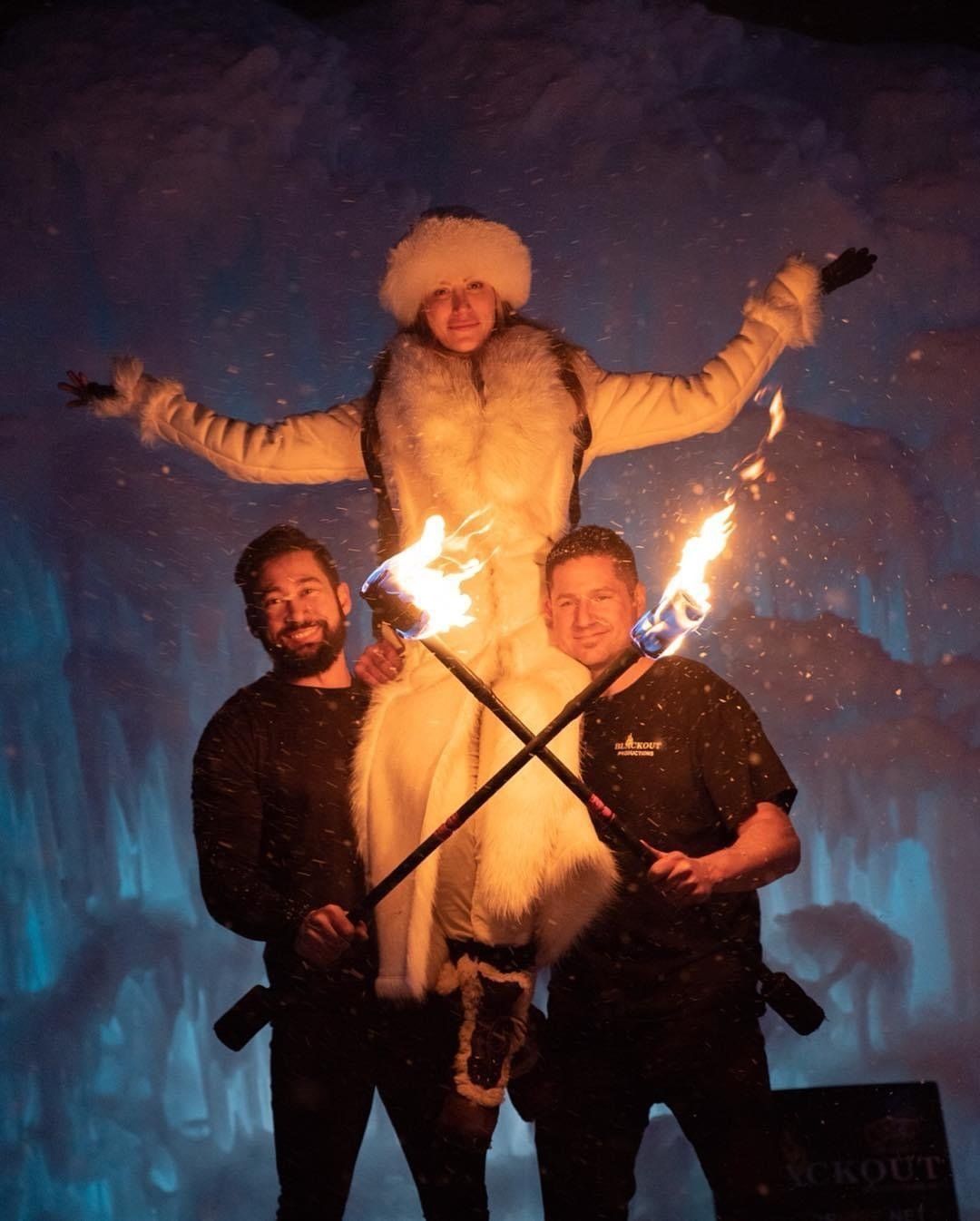 A man and woman are holding a snow queen on their shoulders with fire torches.