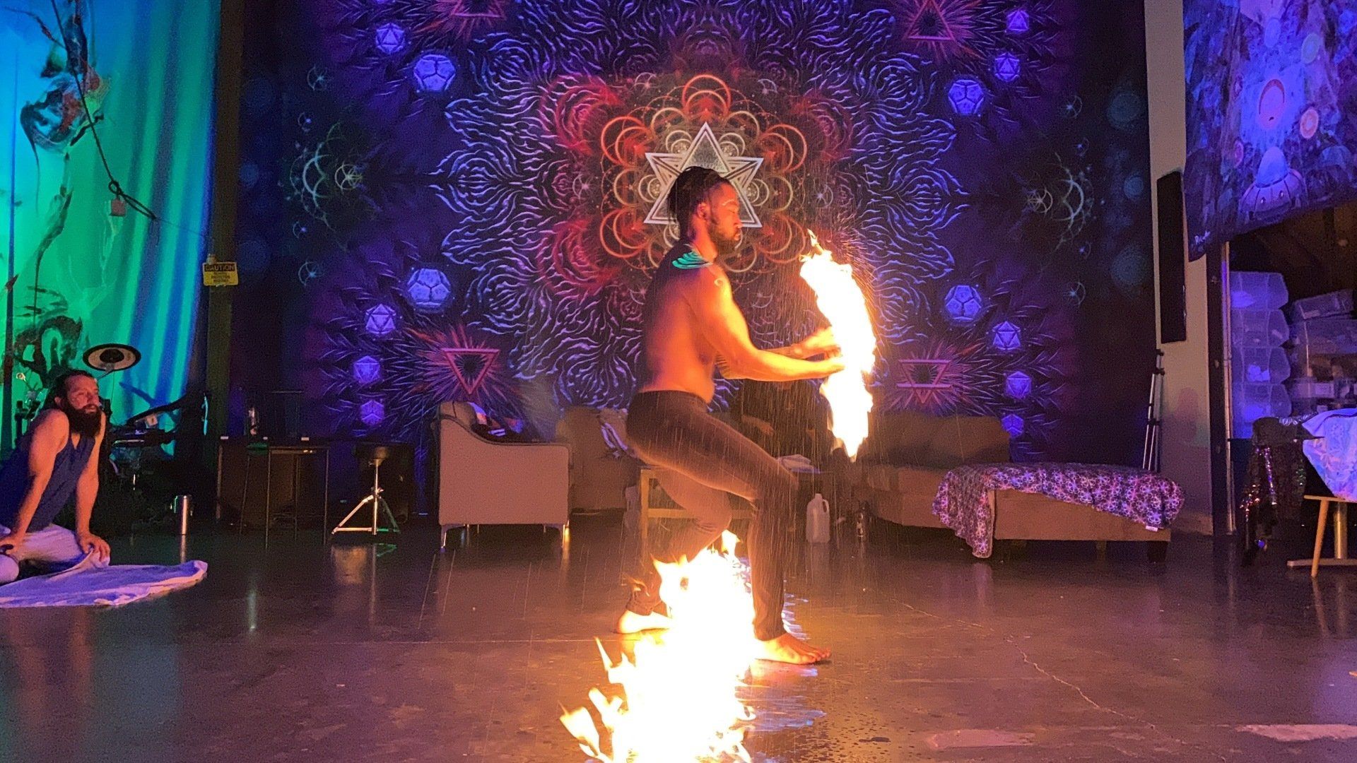 A man is playing with fire on a stage in a room.