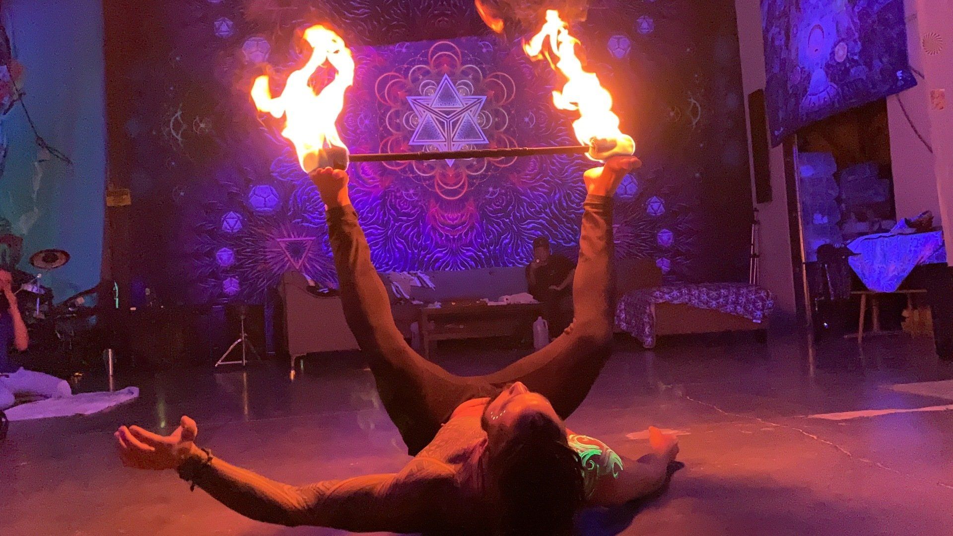 A man is laying on the floor holding a pair of fire sticks.