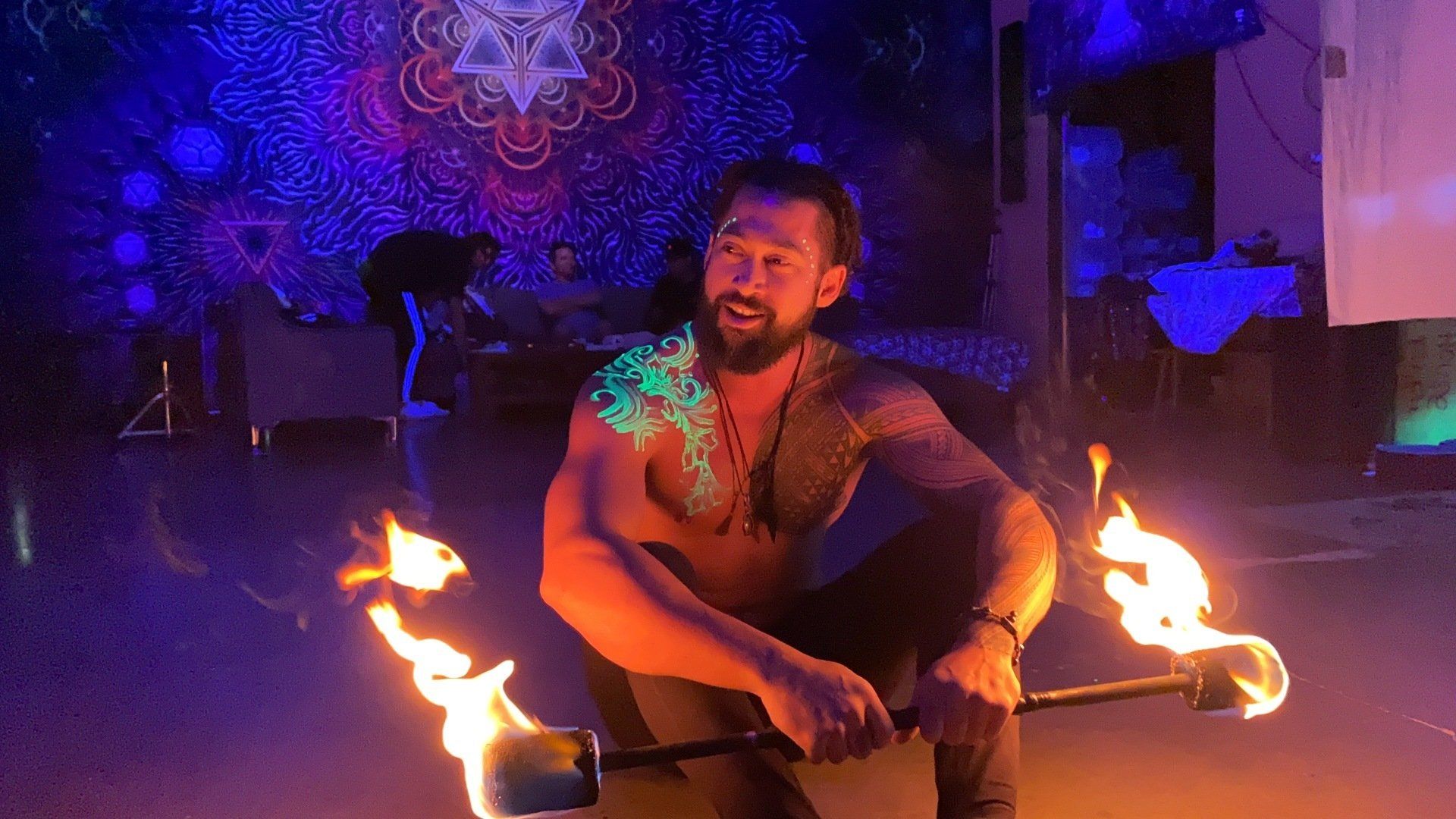 A man sitting holding a fire torch smiling.