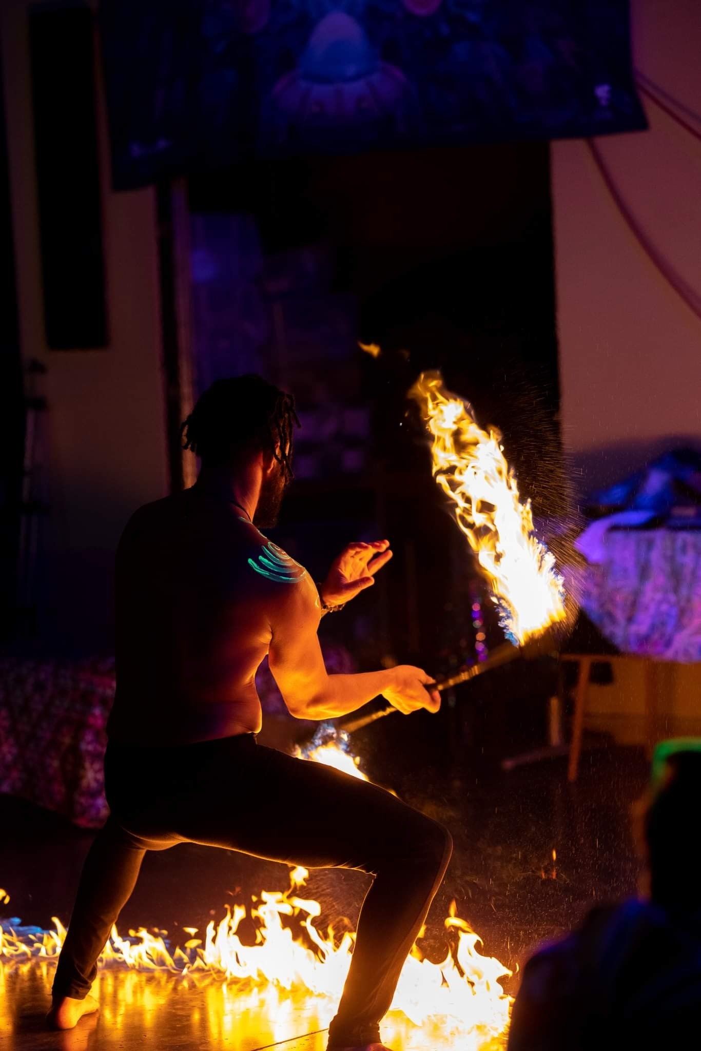 A man is kneeling down in front of a fire.