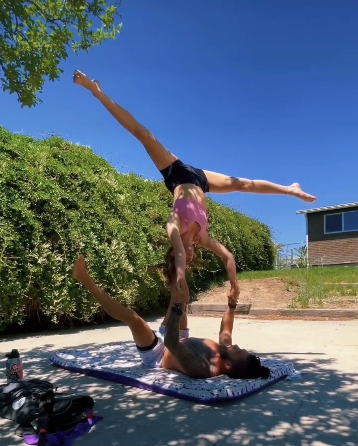 A man and a woman are doing a handstand on a yoga mat.