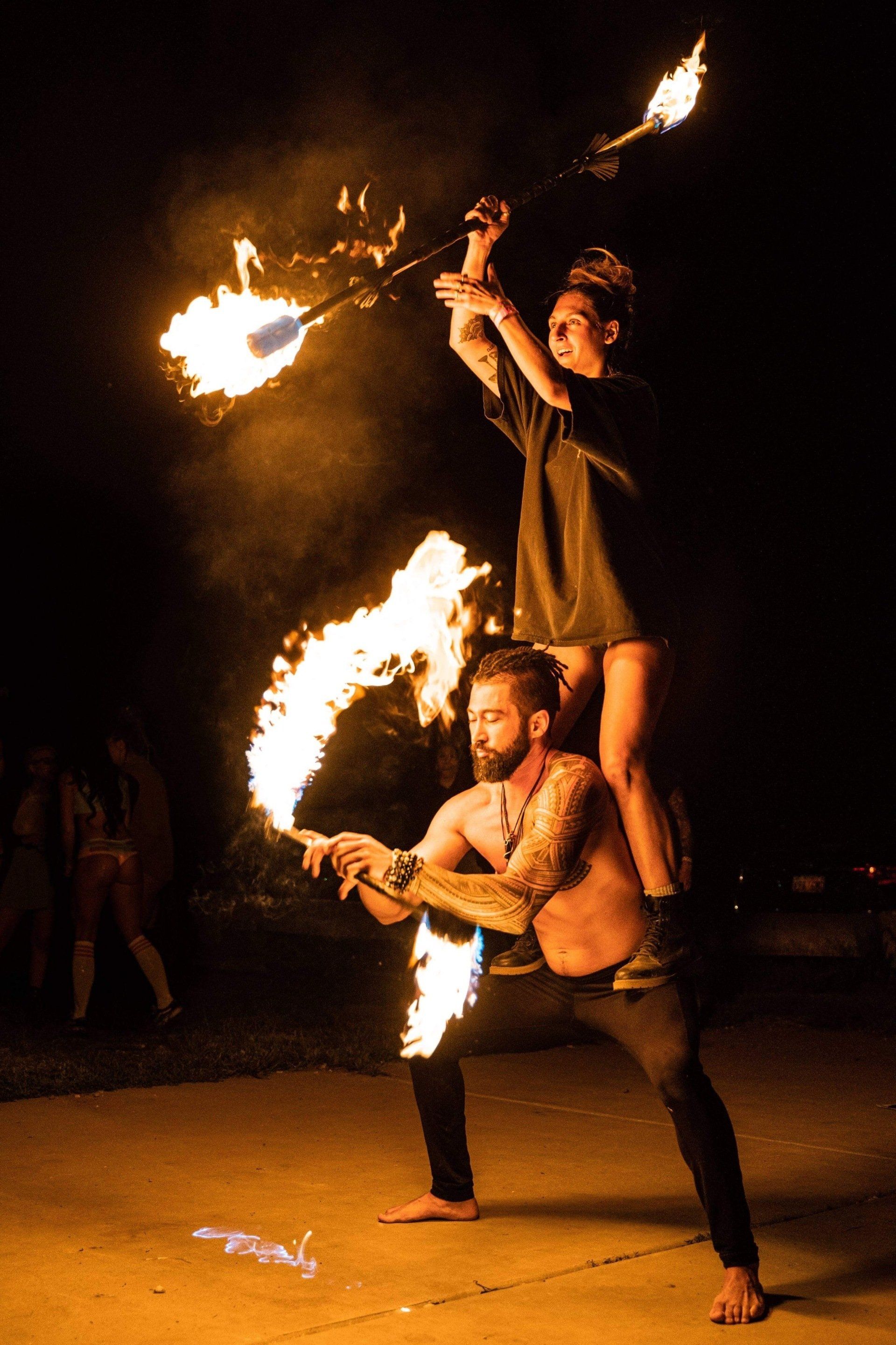 A man and a woman are performing a fire show at night.