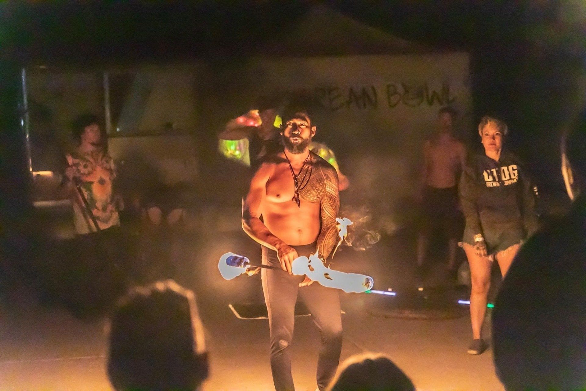 A shirtless man is dancing on a stage in front of a crowd.