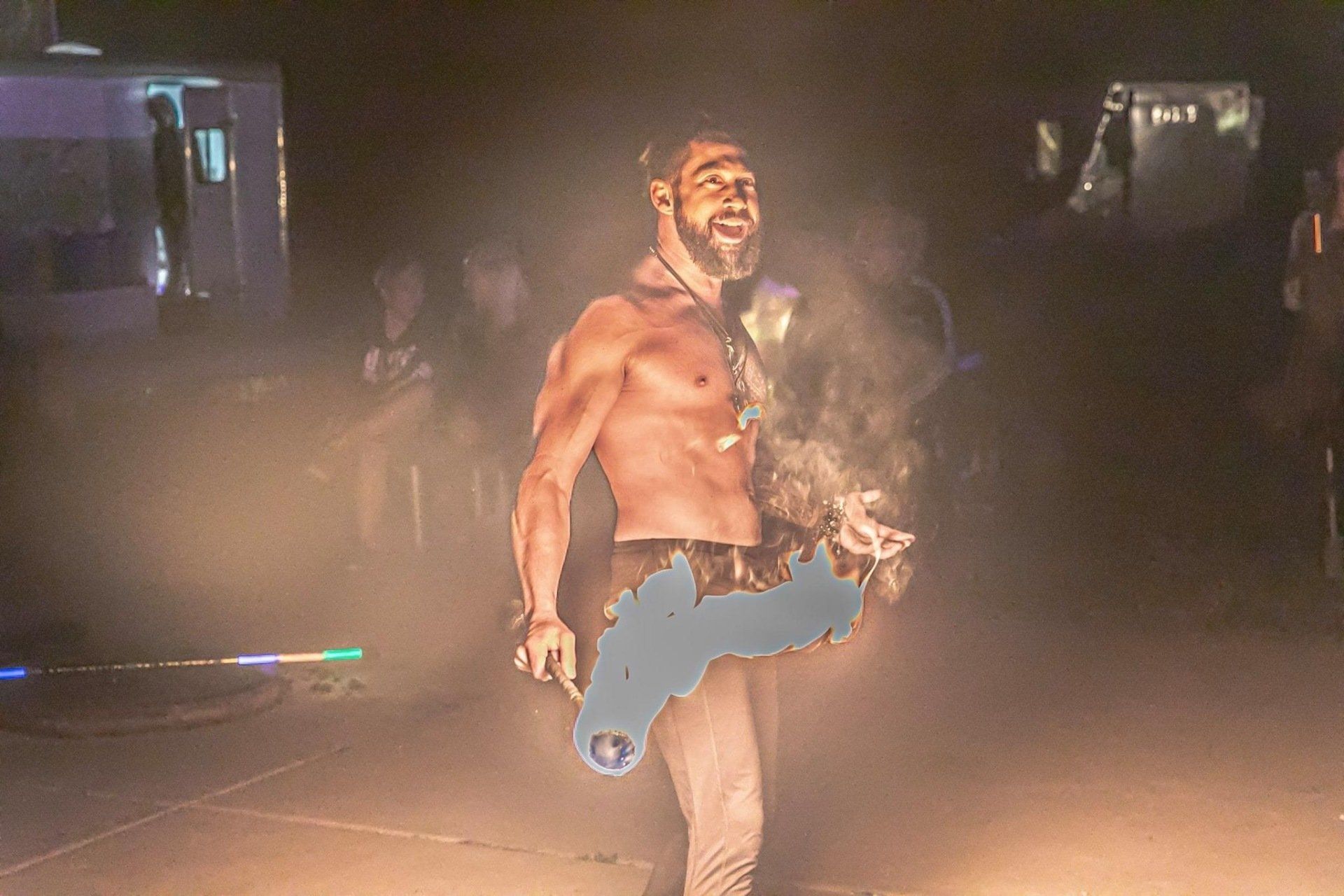 A shirtless man is standing on a stage in a dark room holding a key.