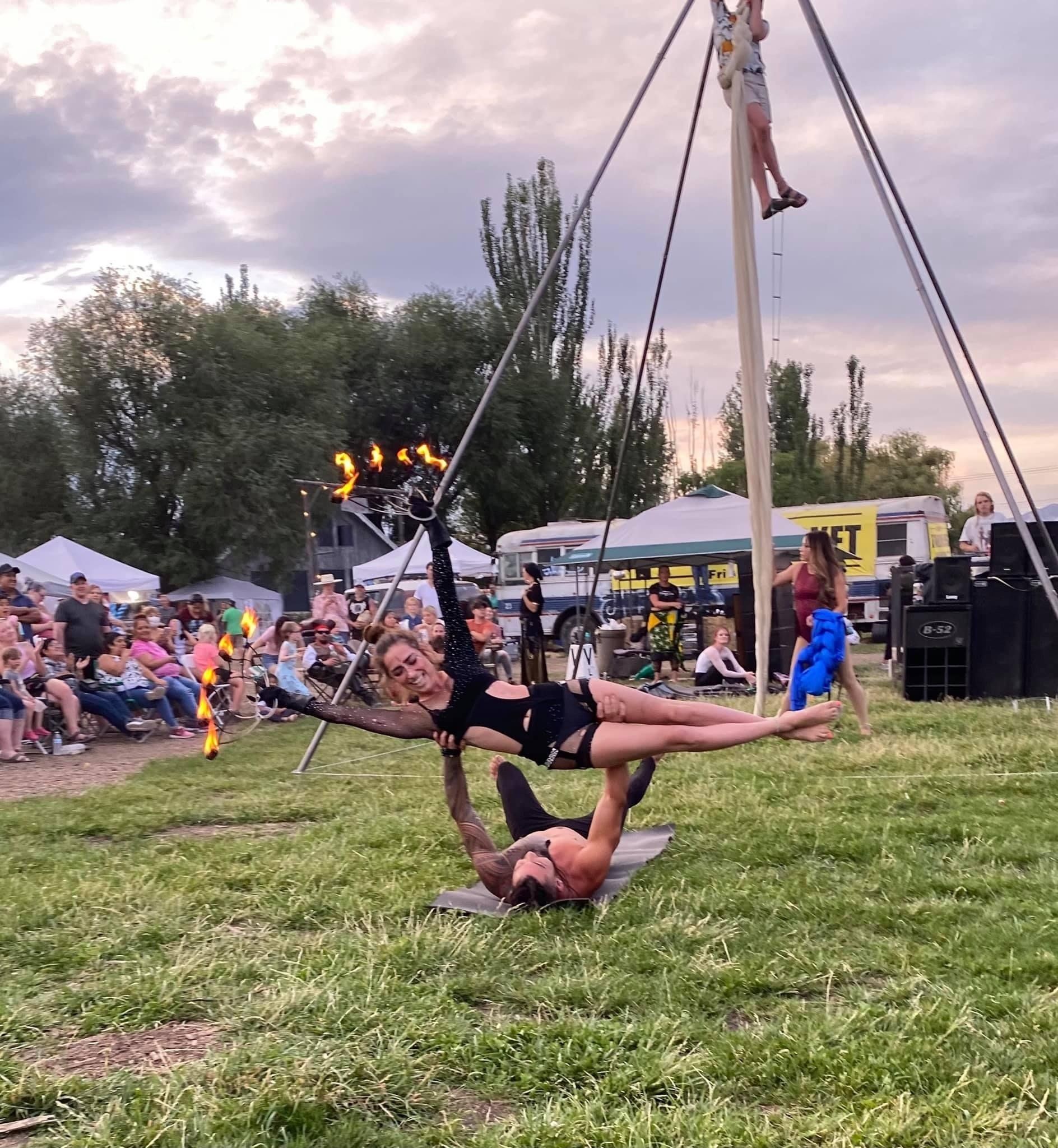 A man and a woman are performing aerial acrobatics in a field.