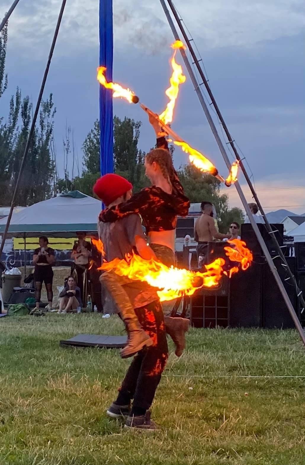 A man and a woman are holding flaming torches in a field.