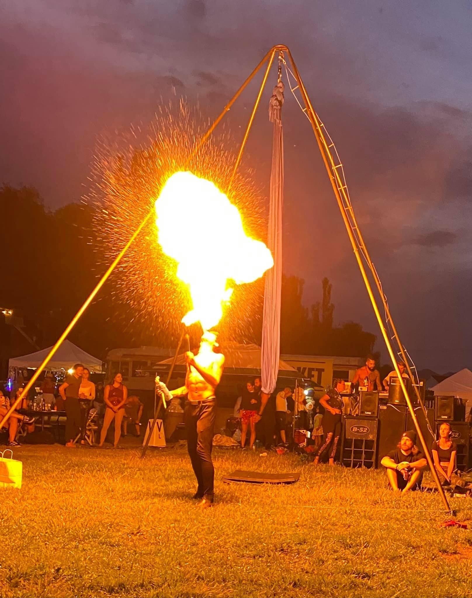 A woman is performing a fire show in front of a crowd