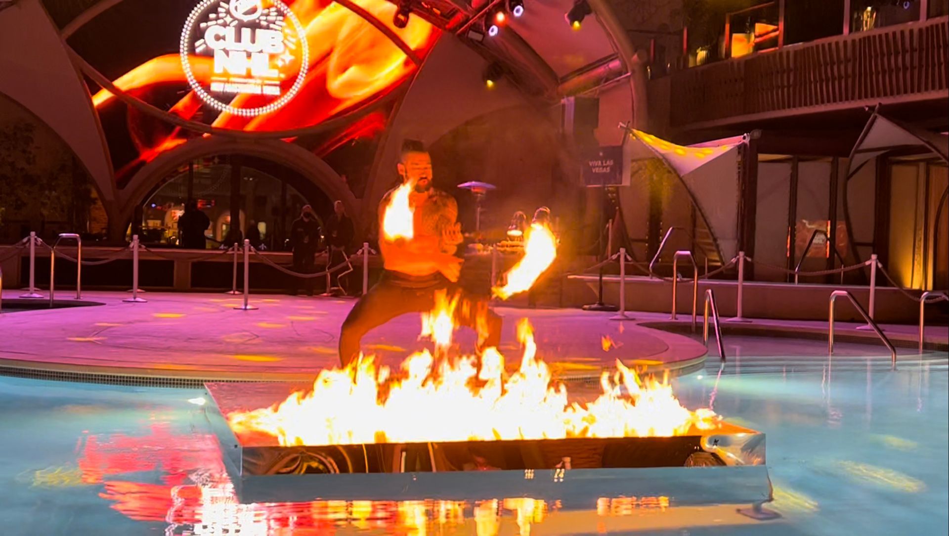 A man is standing in front of a fire pit in a pool.