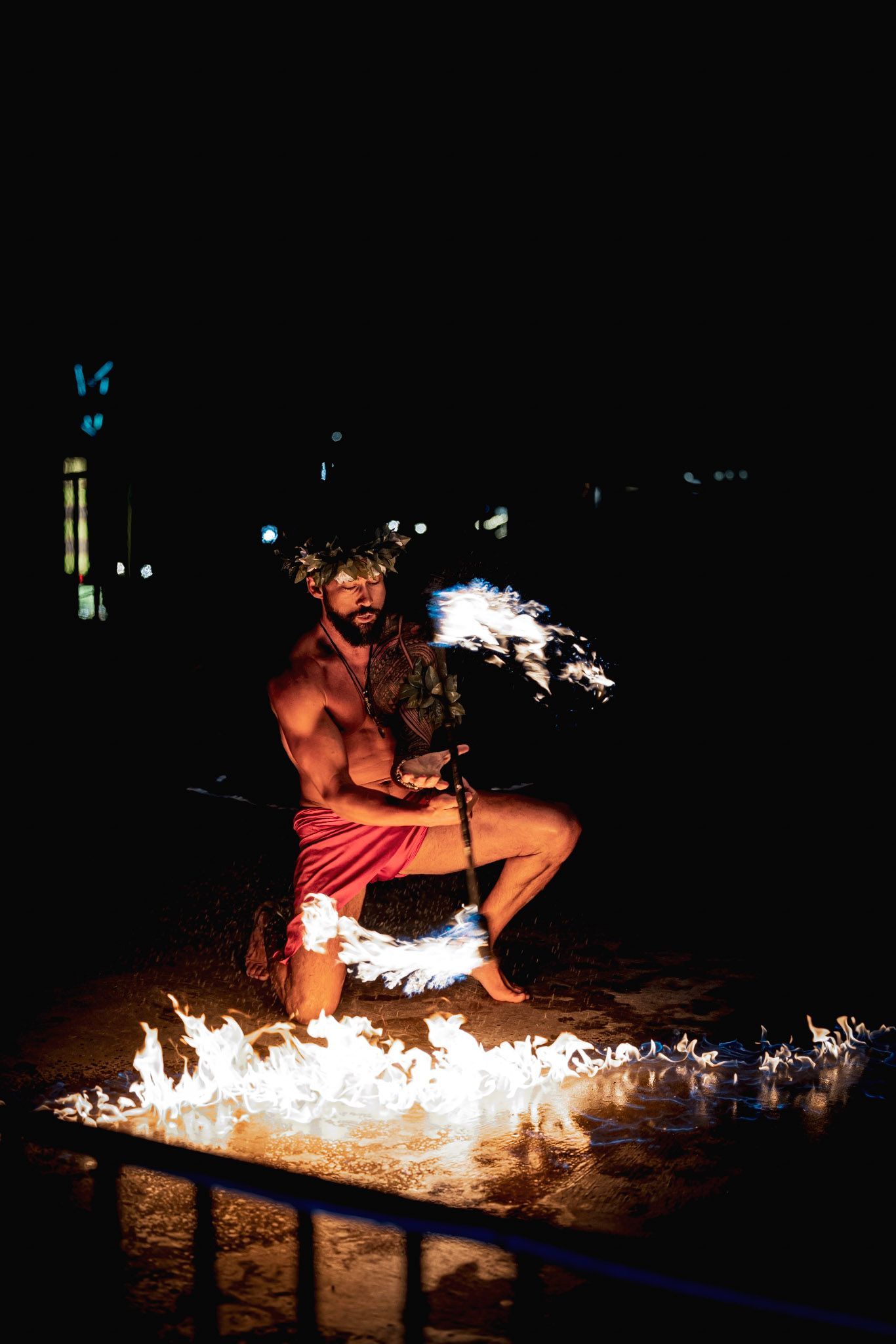 A man is kneeling down in the dark holding a fire ring.