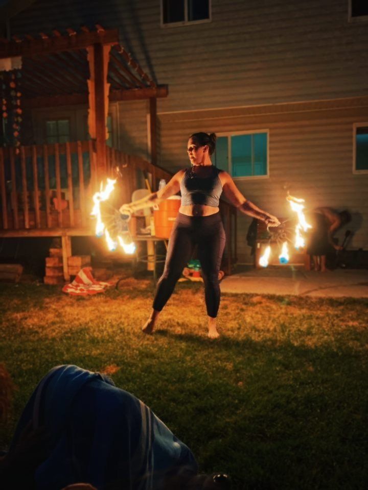 A woman is performing with fire fans.