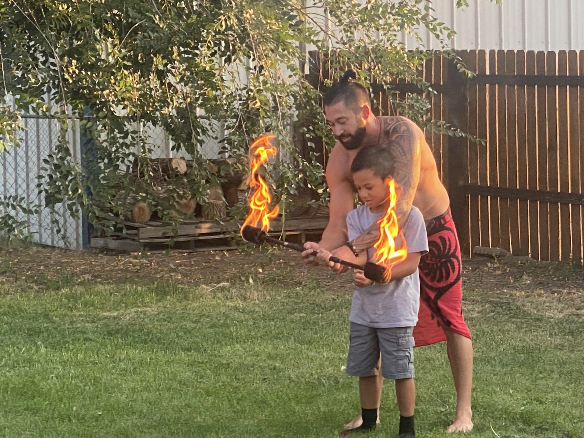 A man and a boy are playing with fire in a backyard.