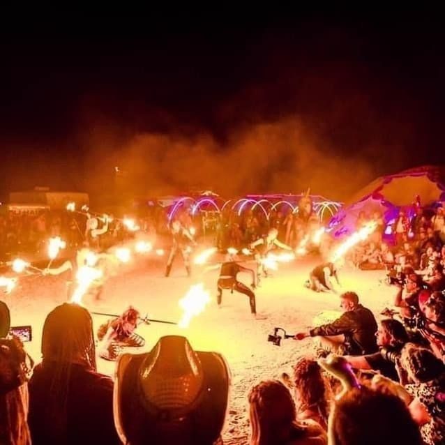 A crowd of people watching a fire show at night