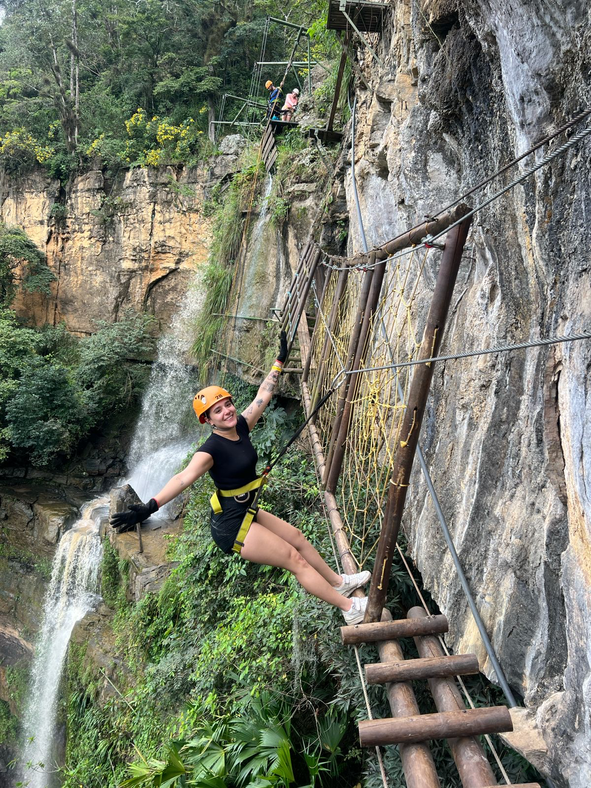A group of people are dancing in a dark room with smoke coming out of the ceiling.