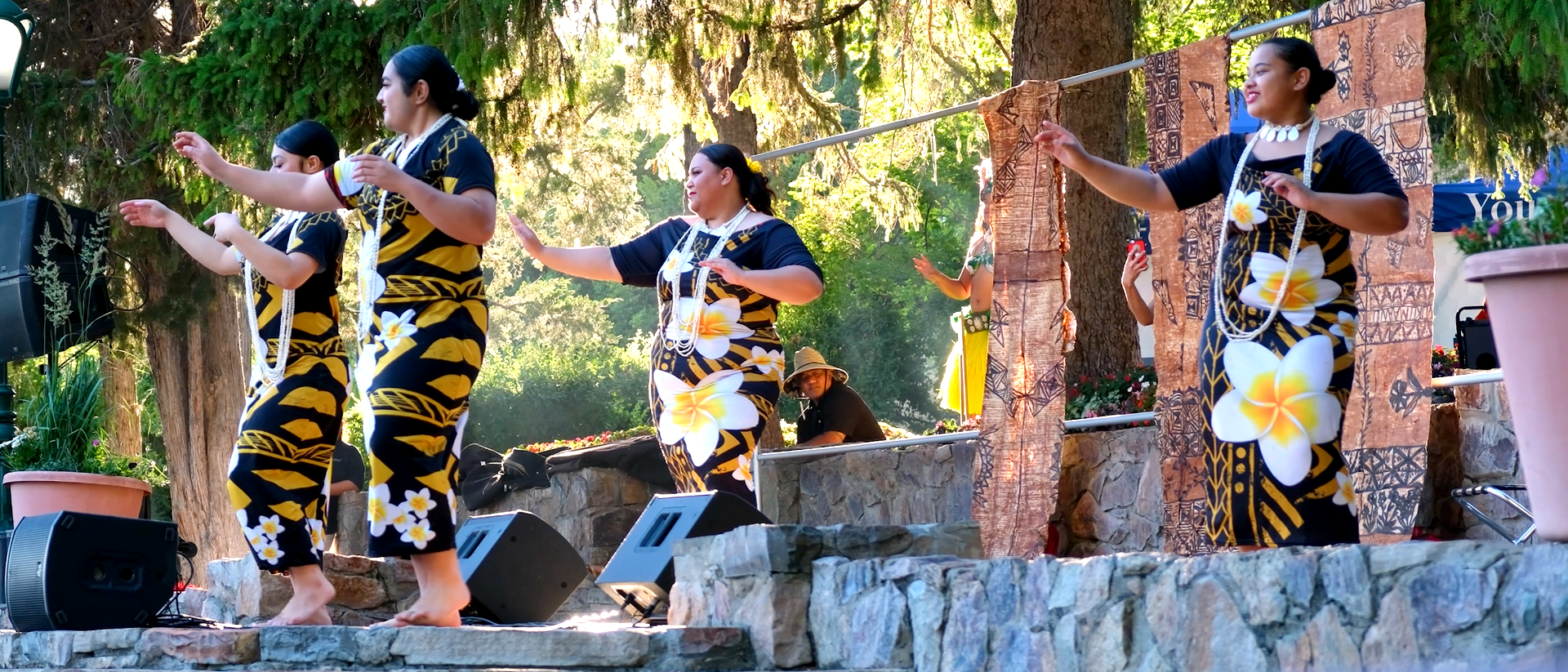 A group of women are dancing on a stage in front of a speaker.