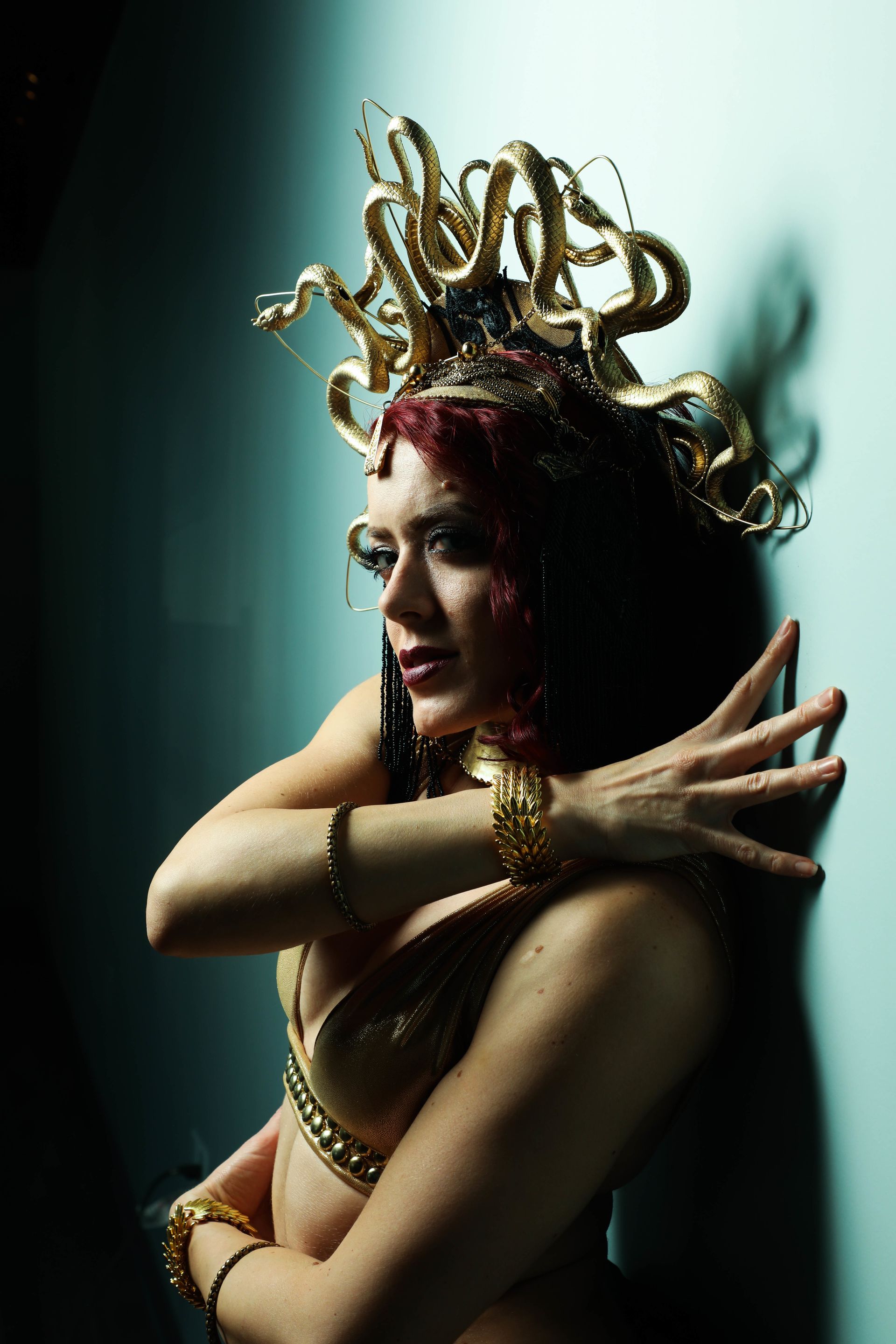 A woman in a medusa costume is leaning against a wall.
