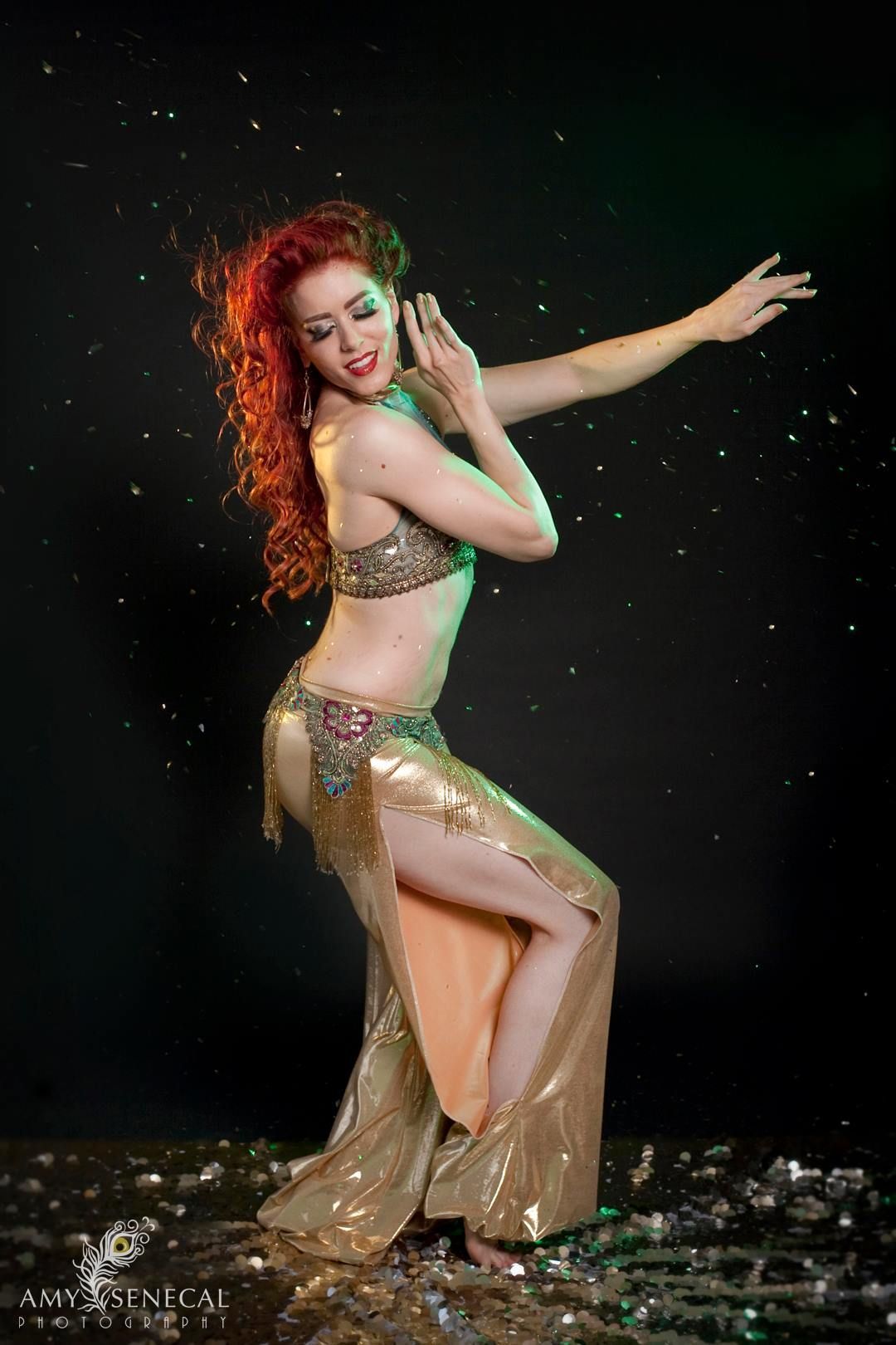 A woman in a belly dancer costume is dancing in the rain.