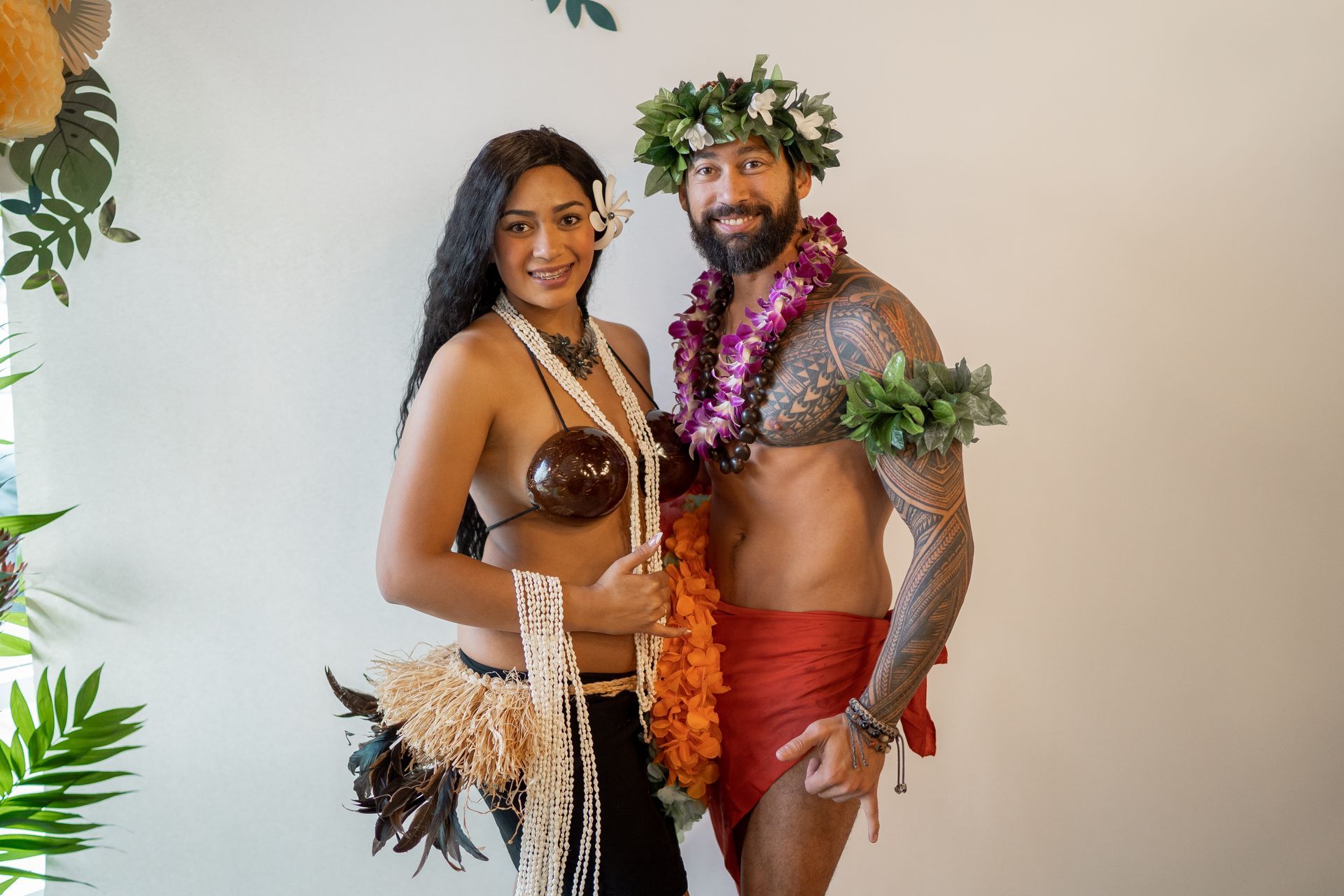 A man and a woman in hawaiian costumes are posing for a picture.