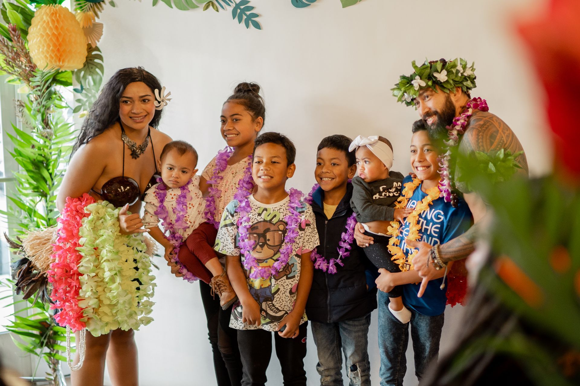 A woman is standing next to a group of children wearing lei.