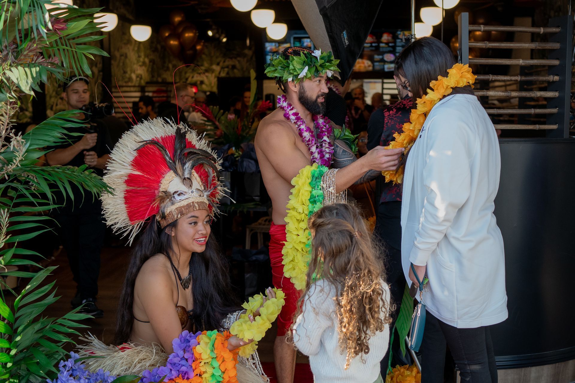 A group of people are standing around a man wearing a lei.