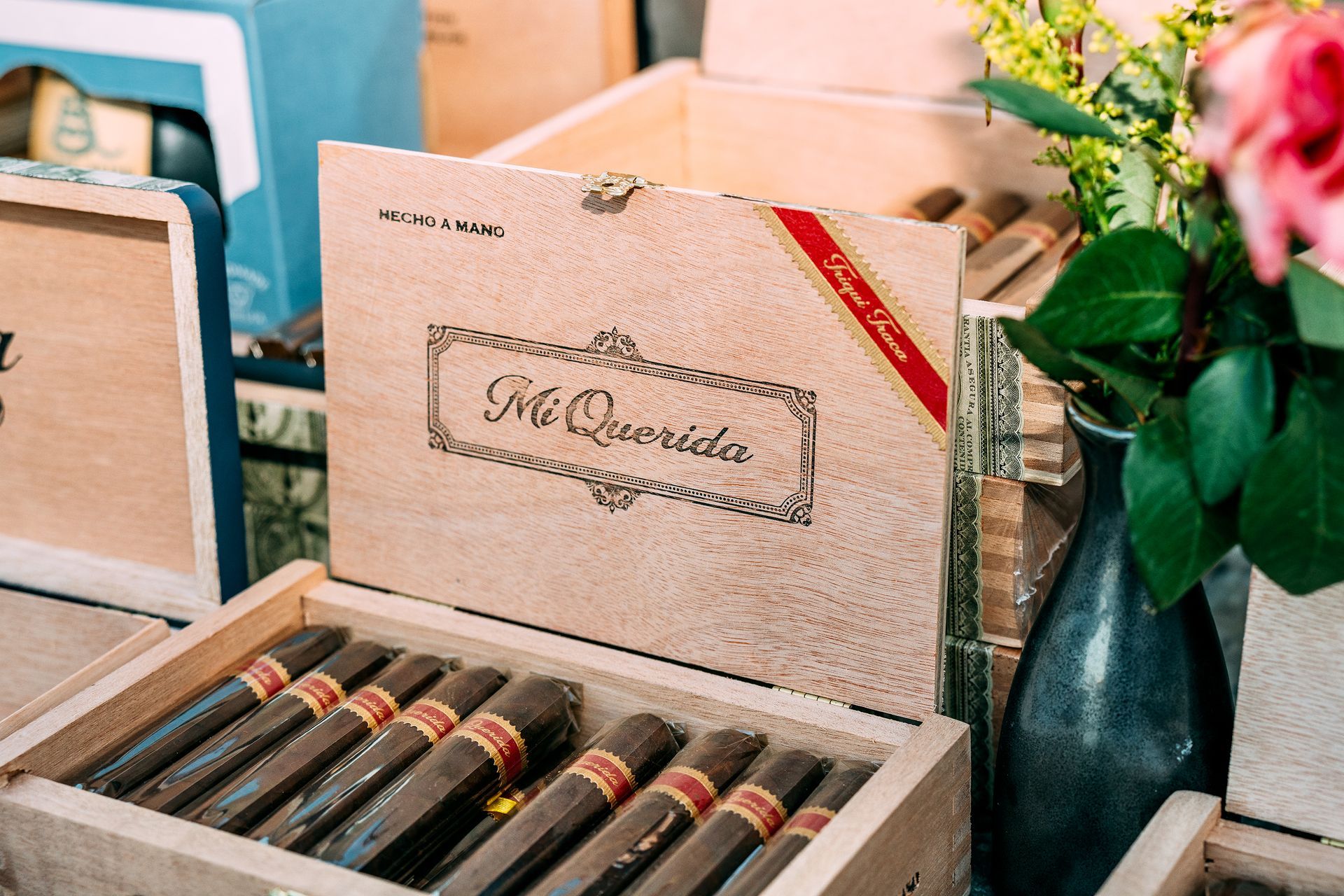A box of cigars is sitting on a table next to a vase of flowers.
