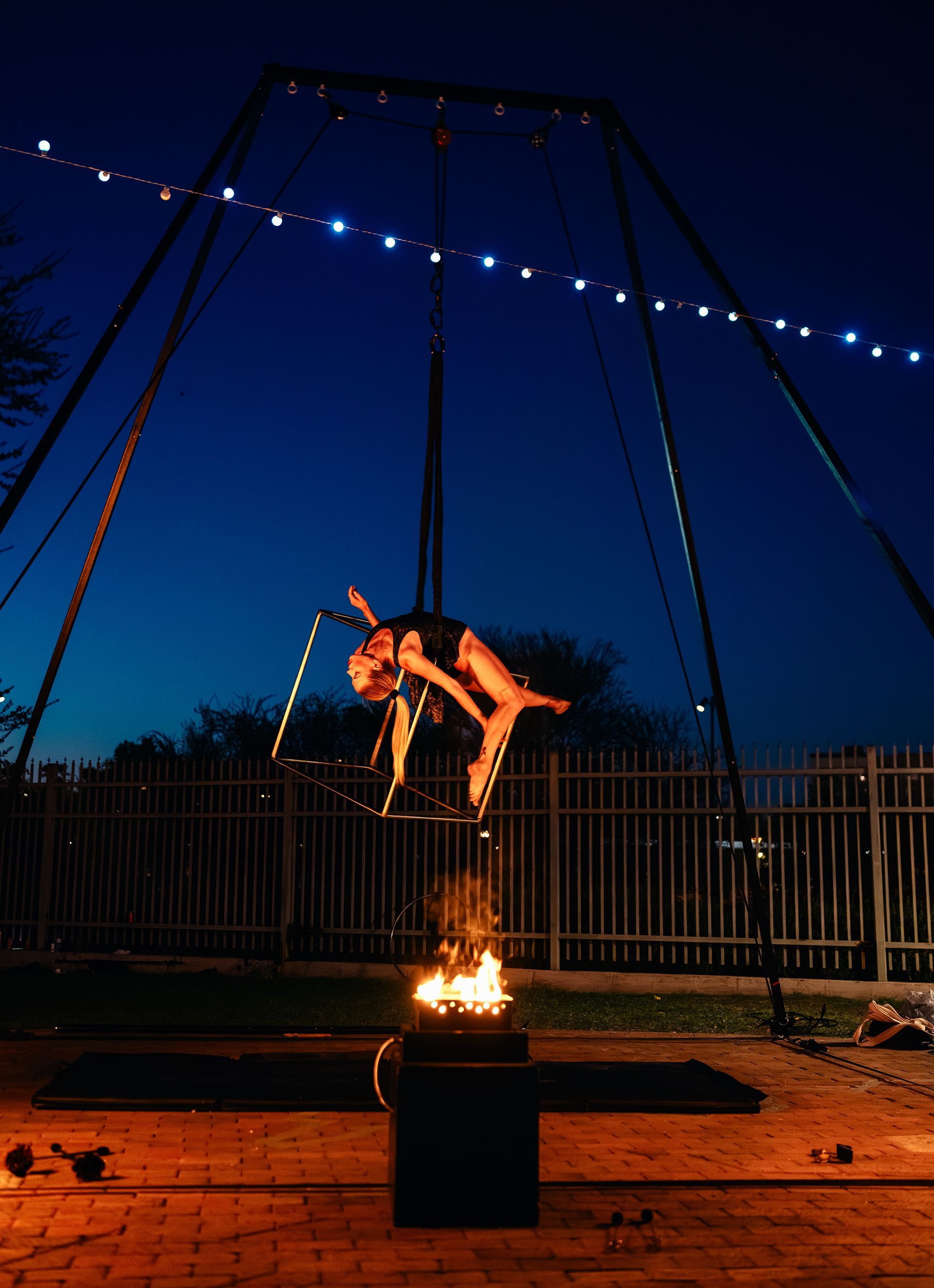 A woman is performing aerial acrobatics in the air at night